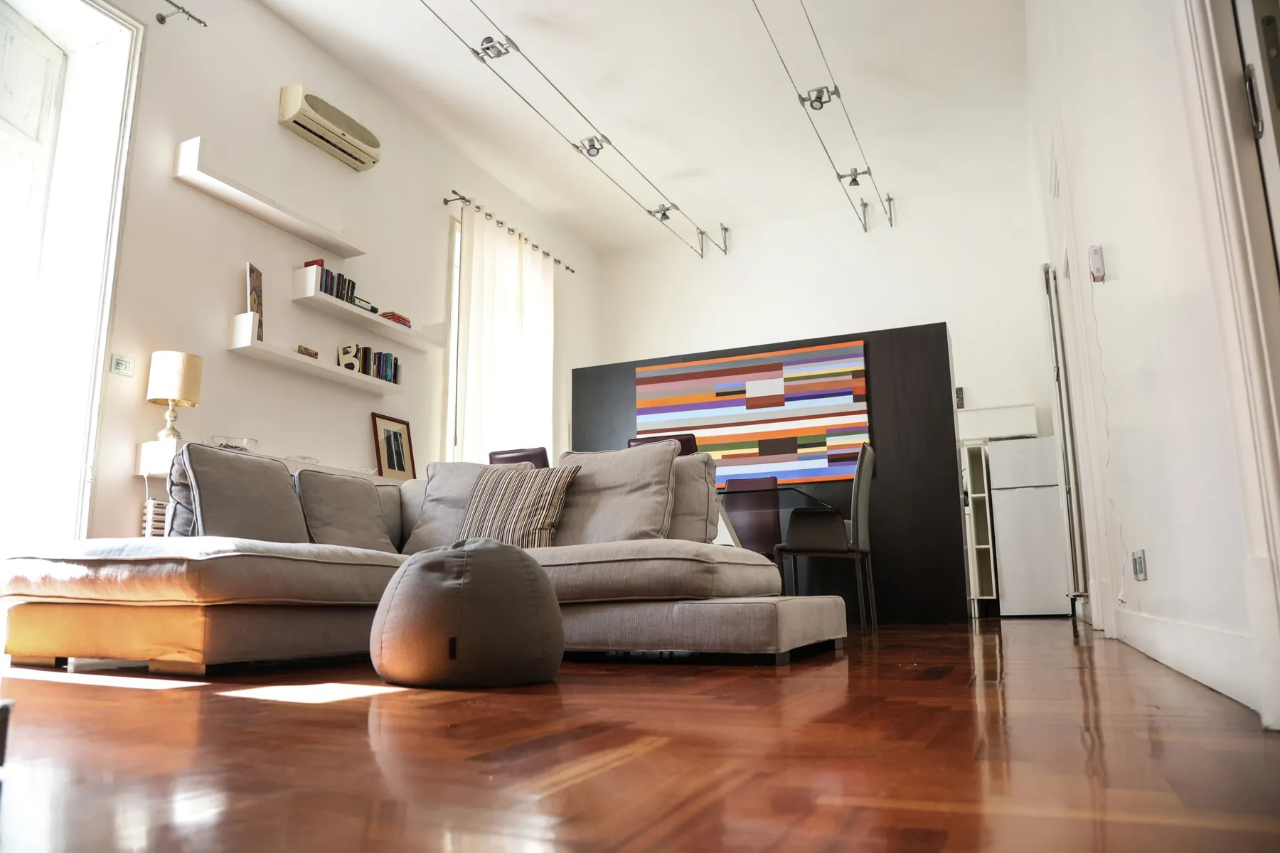 A bright living room with gray seating and colorful horizontal artwork on the wall.