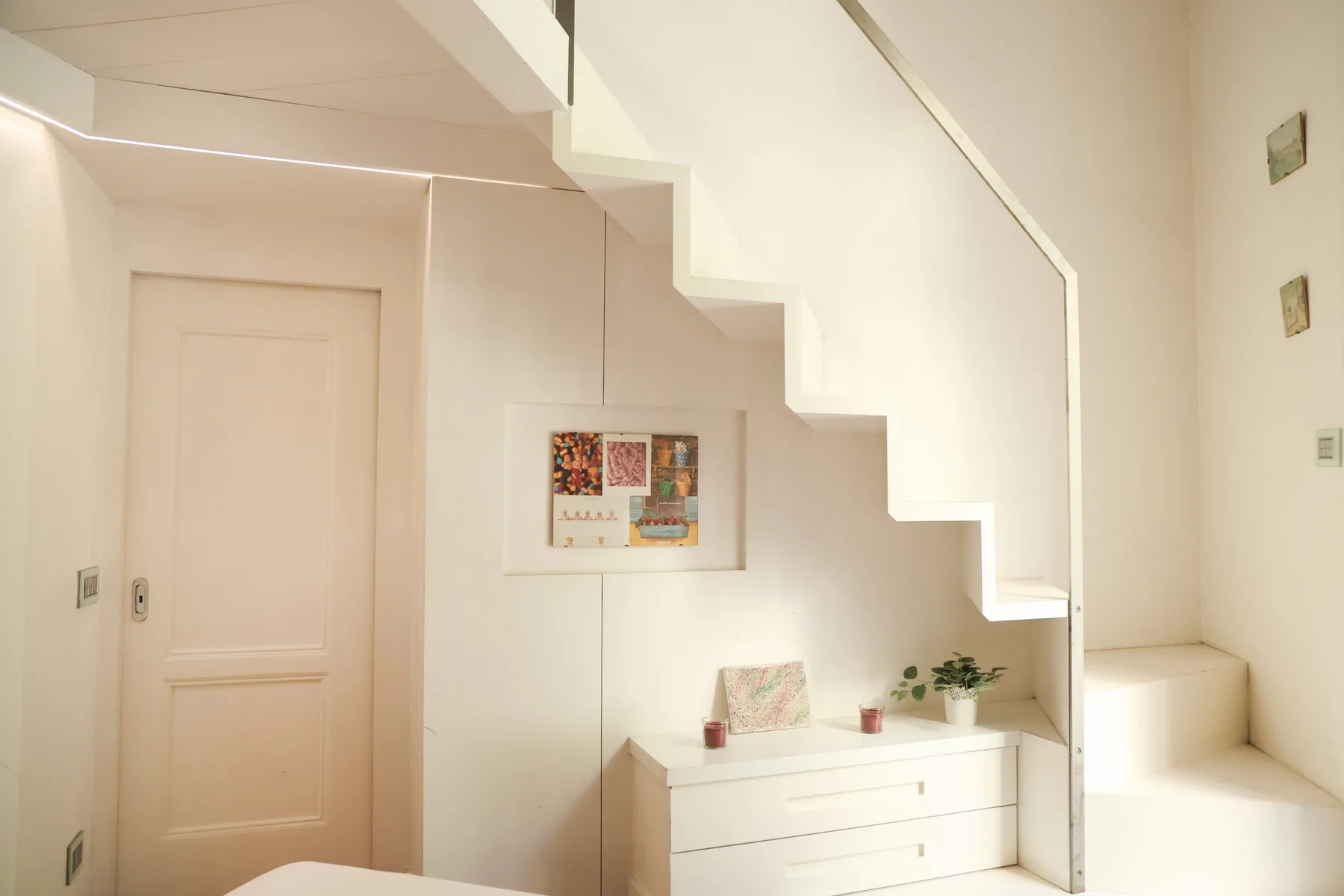A bright interior hallway with a staircase and a small console beneath it.