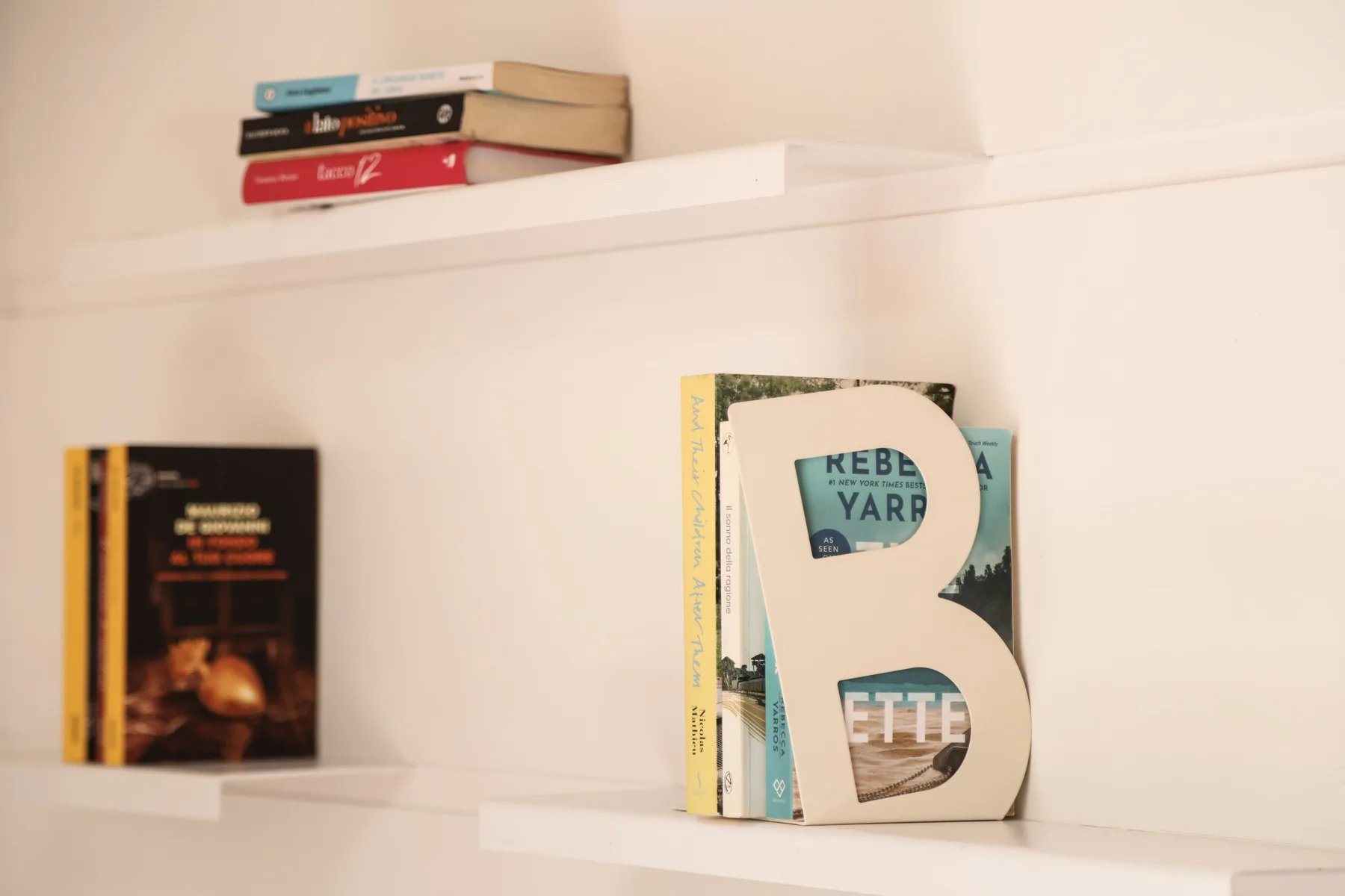 Books and magazines are displayed on white wall shelves.