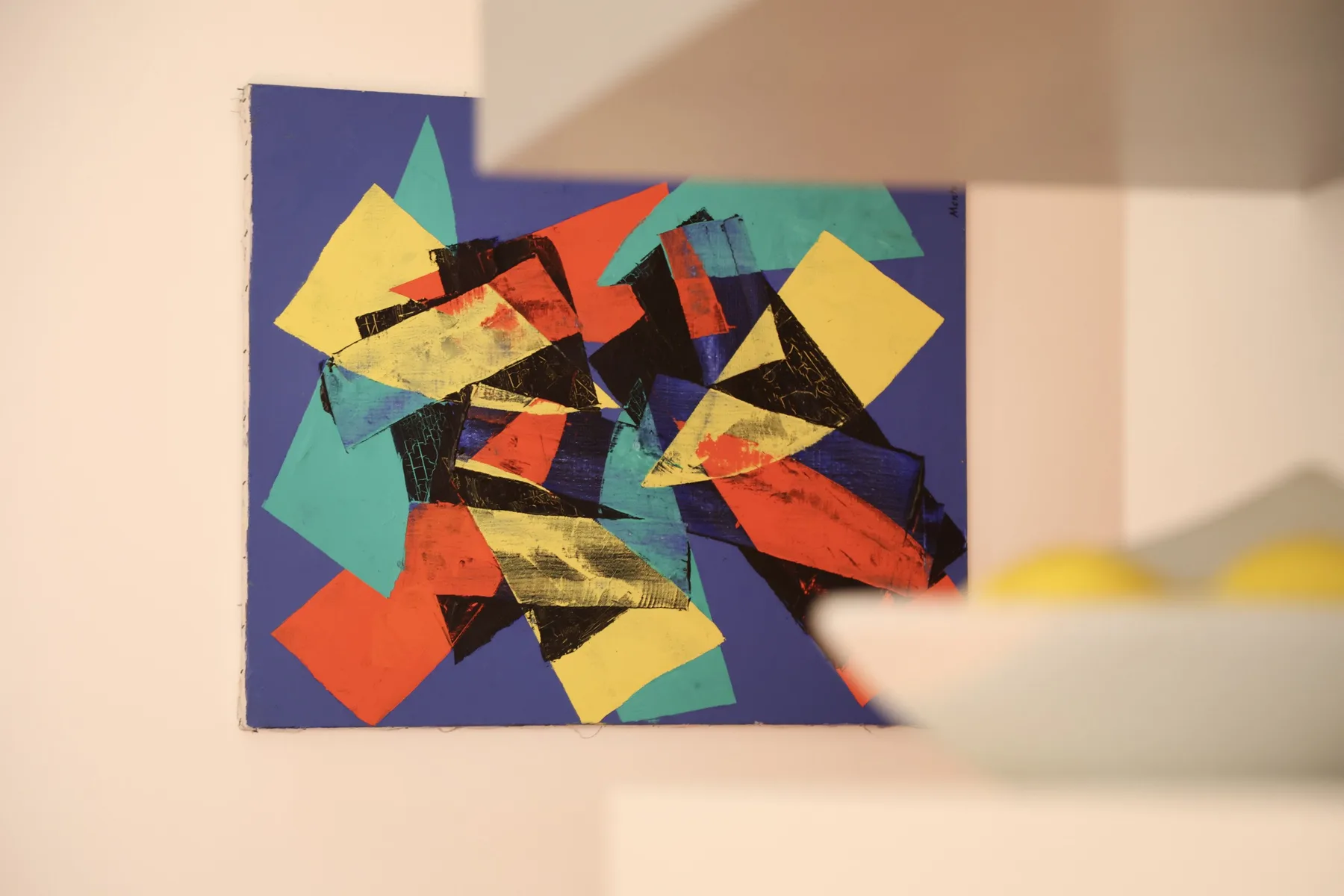 A colorful abstract painting hangs on a light-colored wall.