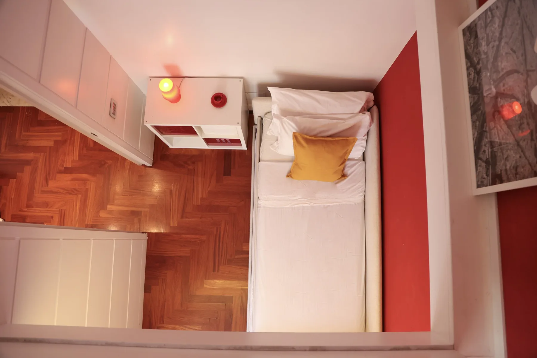 A compact bedroom with a single bed, white bedding, and a yellow pillow.
