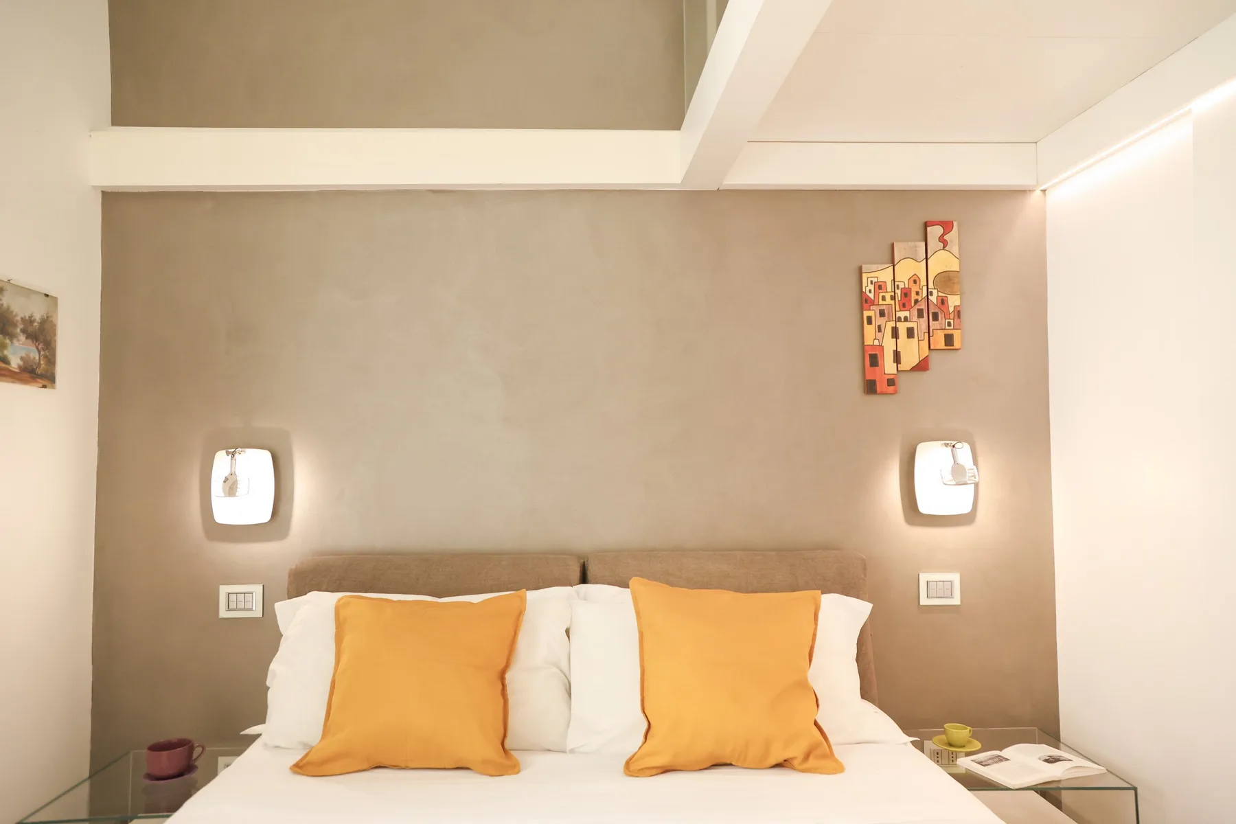 A bedroom with a bed dressed in white linens and orange pillows.