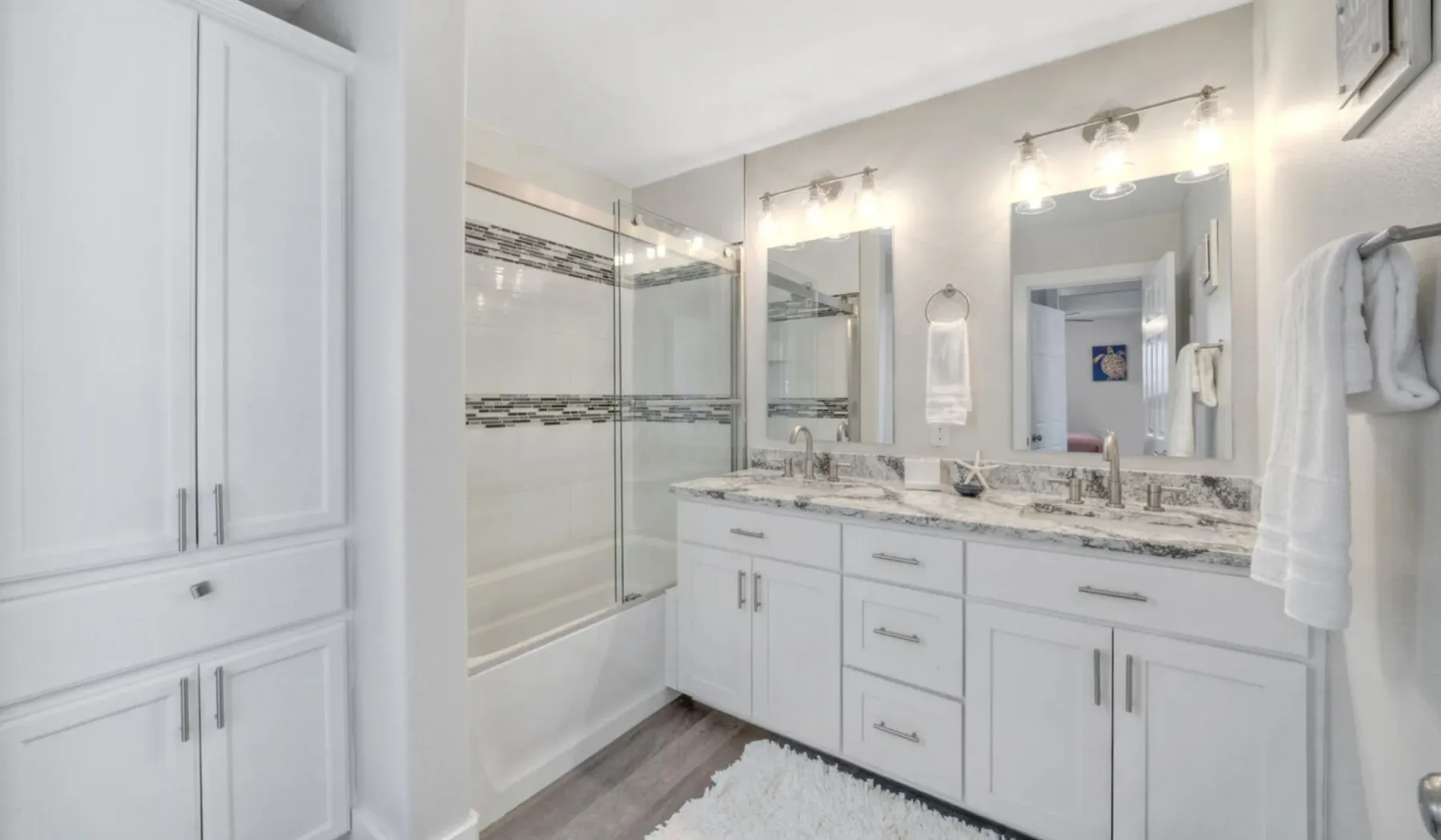 Un baño luminoso con un tocador de doble lavabo y una ducha con mampara de vidrio.