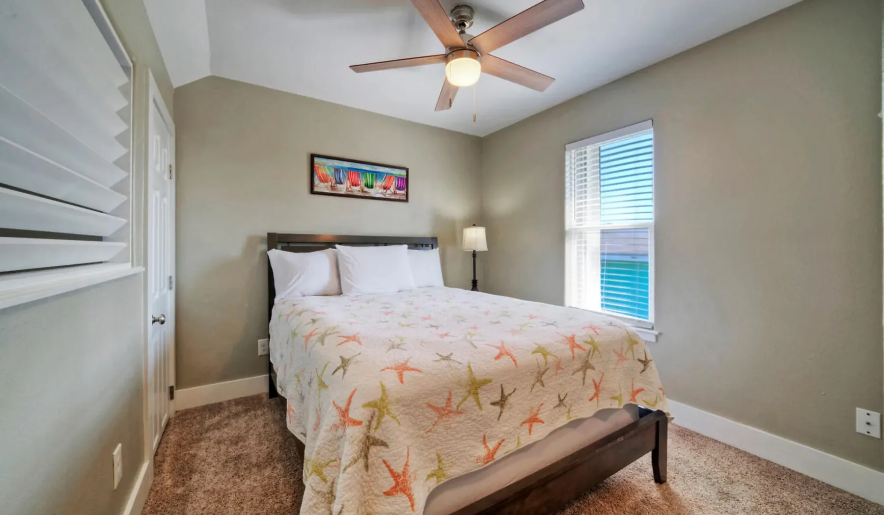 Un dormitorio con una cama cubierta por una colcha colorida con motivos de estrellas de mar.