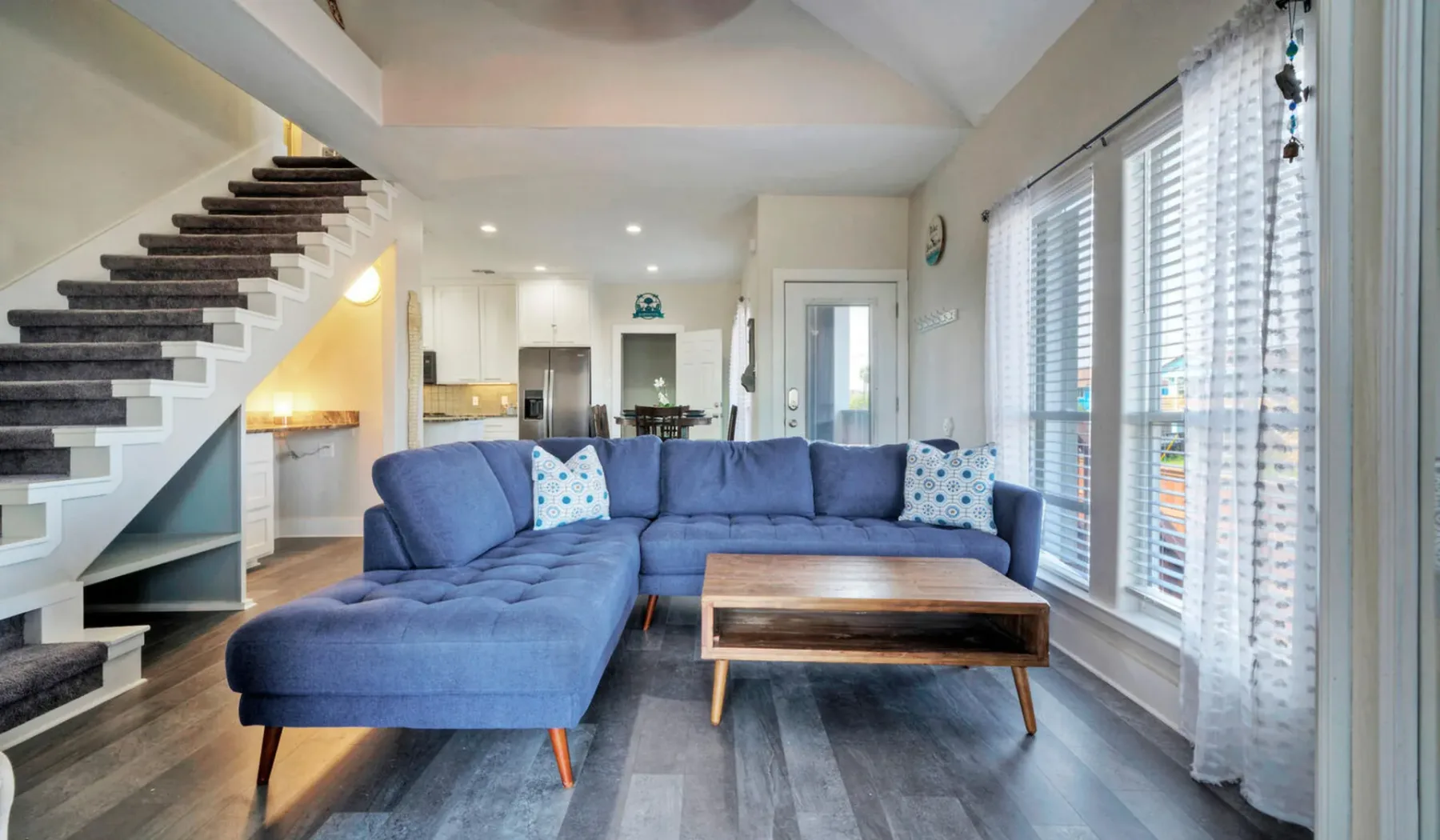 Una sala de estar con un sofá seccional azul y una mesa de centro de madera.