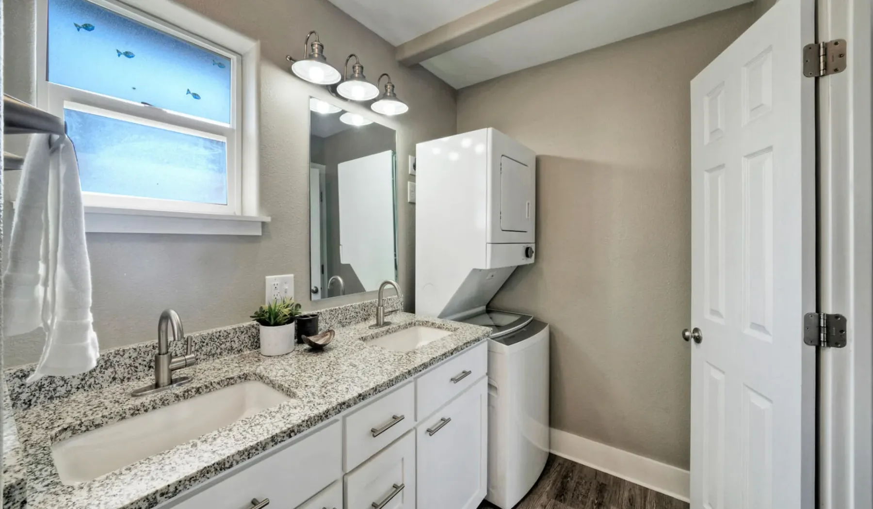 Un tocador de baño con lavabo, espejo y electrodomésticos de lavandería.