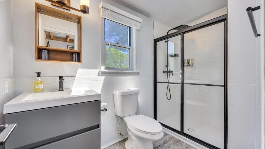 A bright bathroom with a vanity, toilet, and glass shower.
