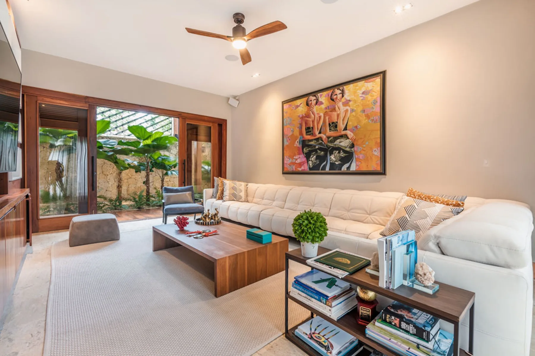 A bright living room with a large sectional and glass doors opening to a garden.