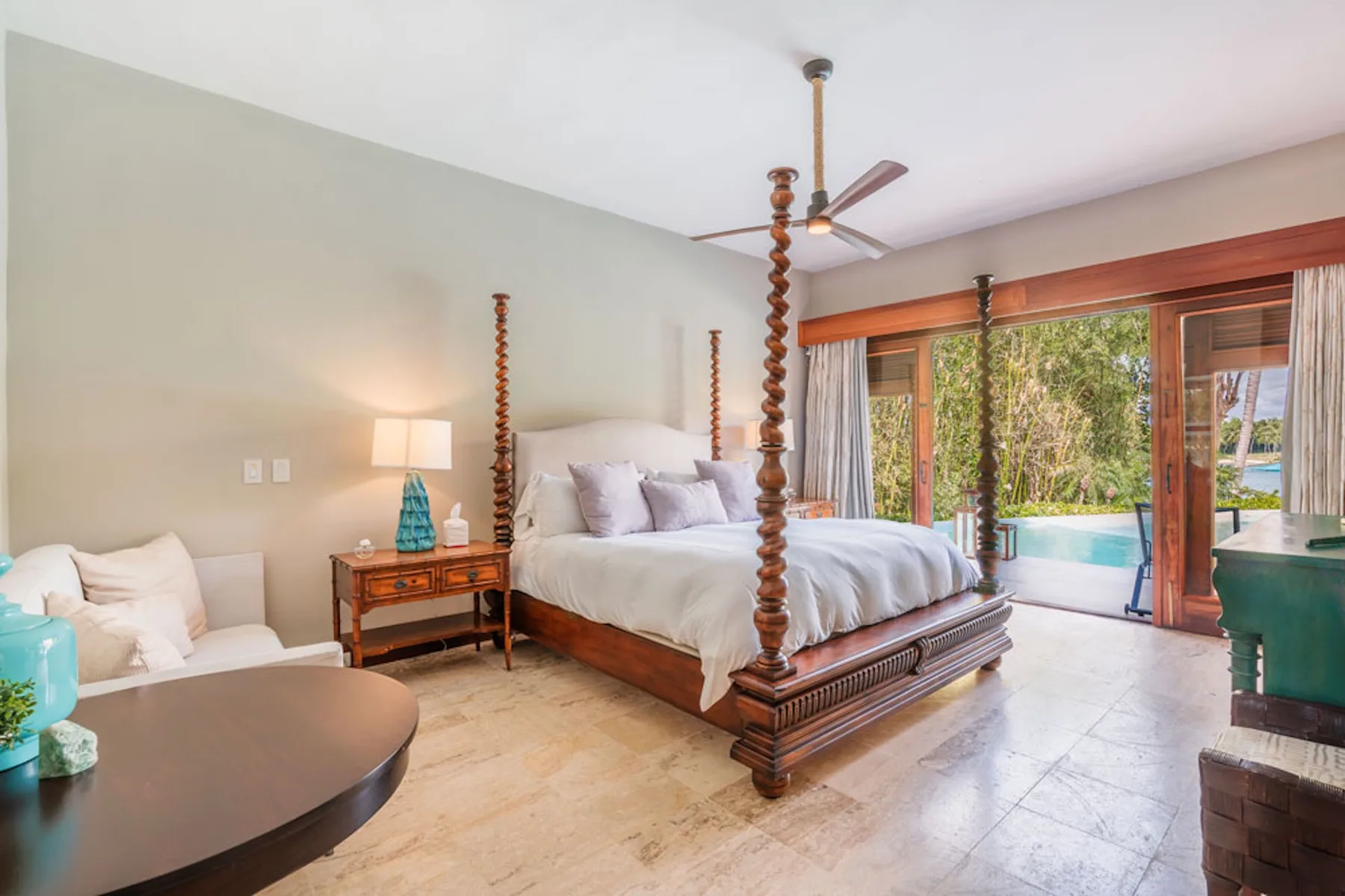 A bedroom with a large wooden bed beside glass doors opening to a garden.