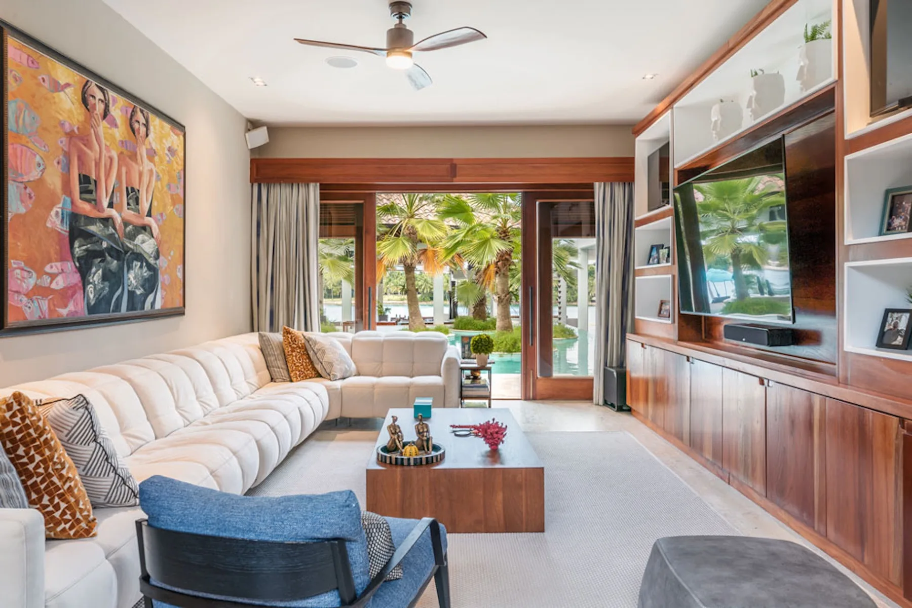 A bright living room with a sectional seating area and glass doors opening to greenery.