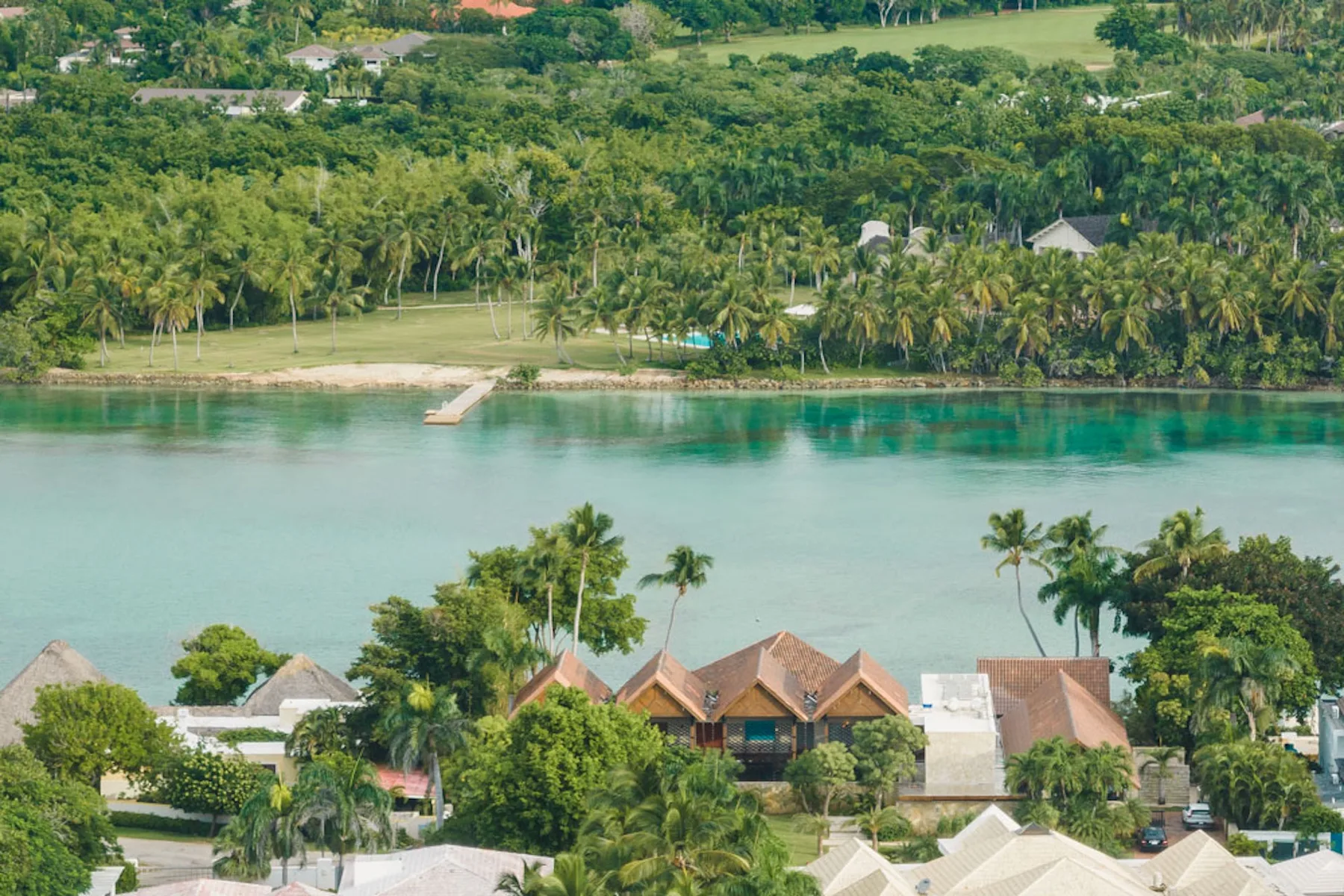 Aerial view of a tropical waterfront with turquoise water and palm trees.