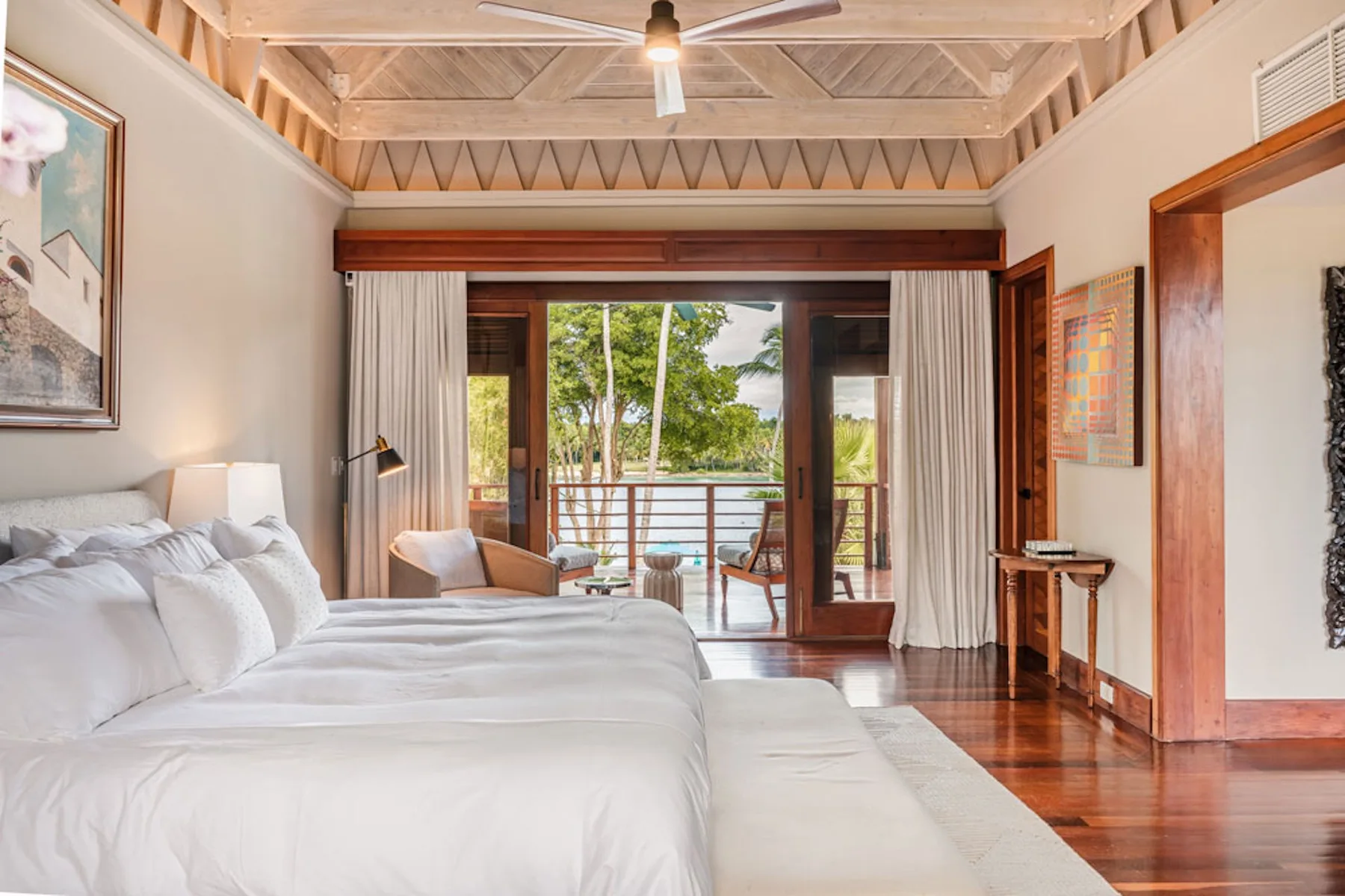 A bright bedroom with a large bed facing open doors to a balcony.