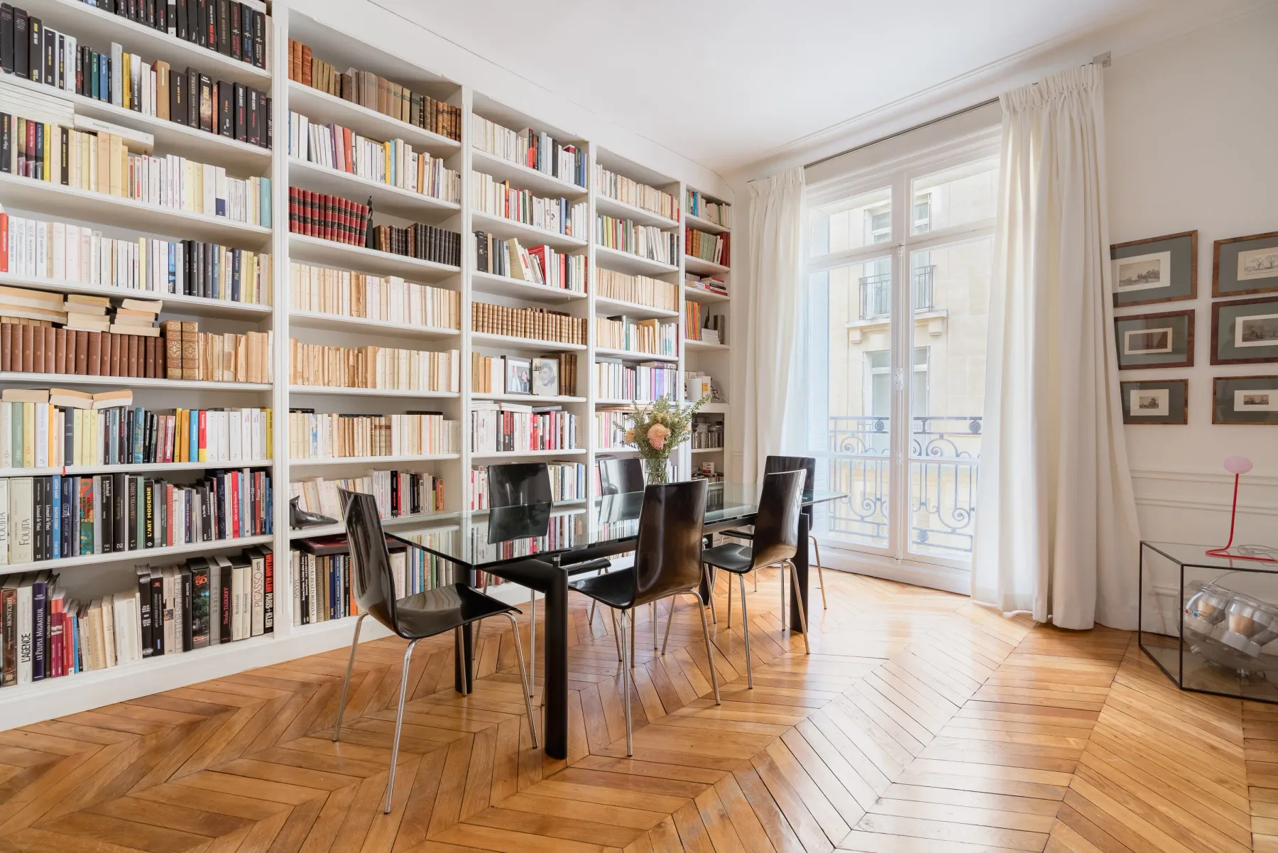 Una luminosa biblioteca y zona de comedor con estanterías altas y una mesa.