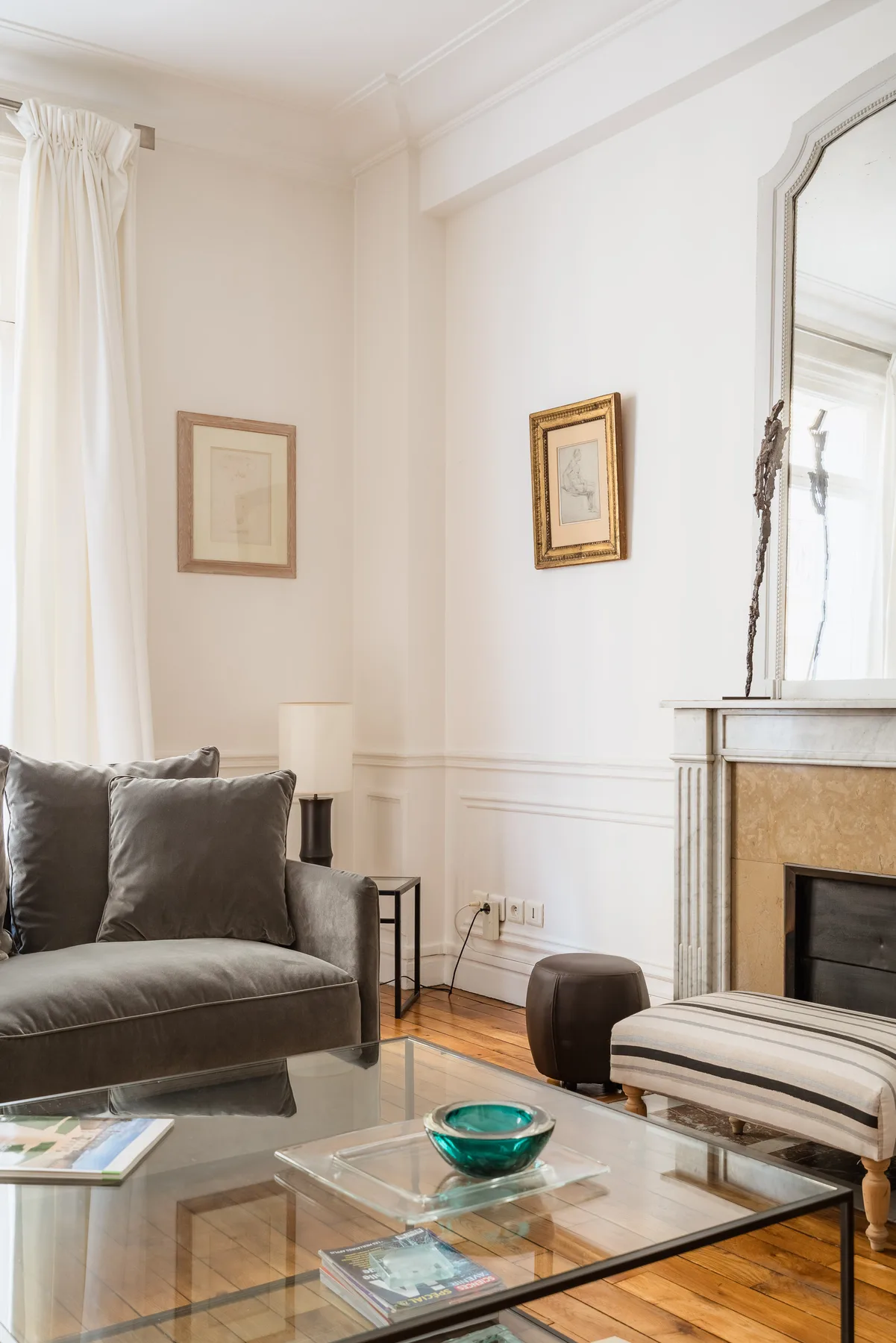 Una sala de estar luminosa con sofá, mesa de centro de vidrio y chimenea.