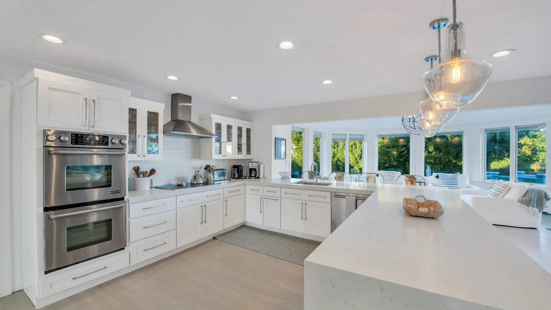 Una cocina luminosa con gabinetes blancos, electrodomésticos de acero inoxidable y una isla grande.