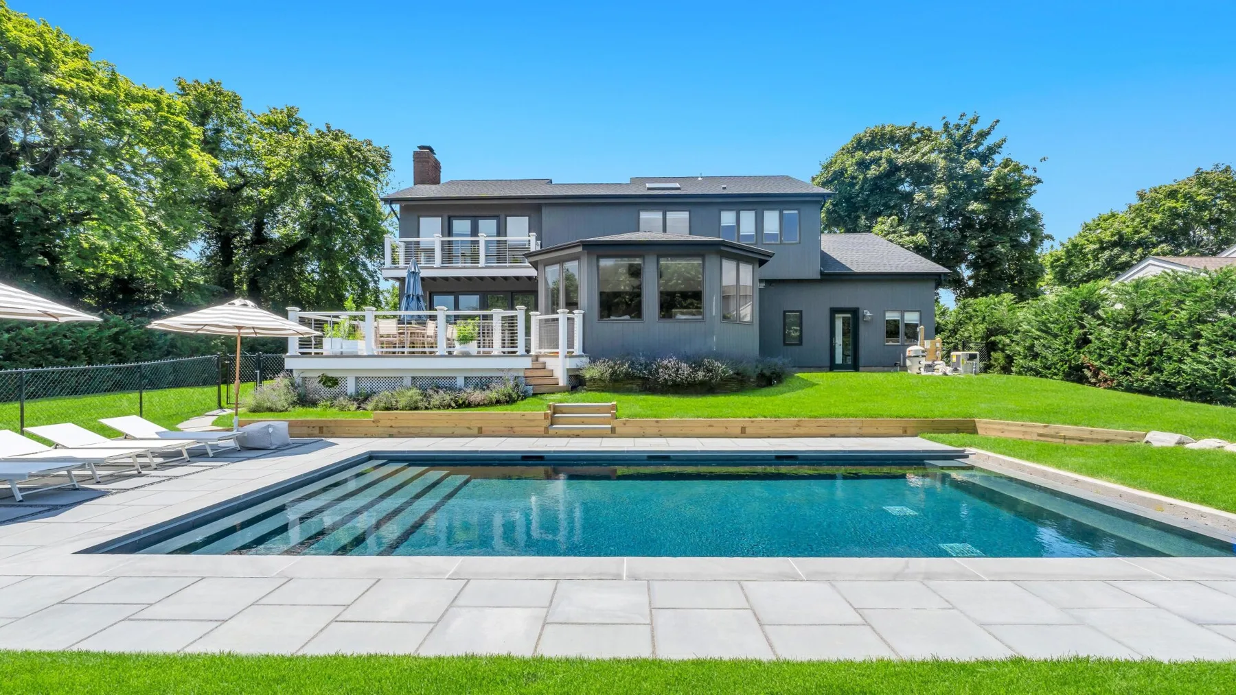Una casa moderna da a una piscina y un patio pavimentado.