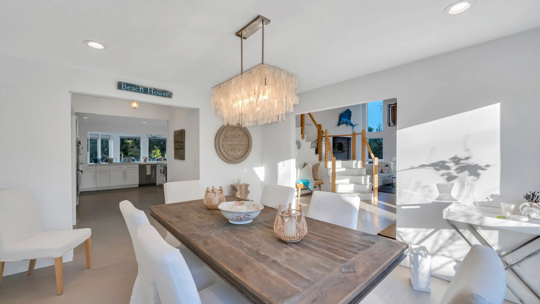 Un comedor luminoso con una mesa larga de madera y una lámpara colgante.