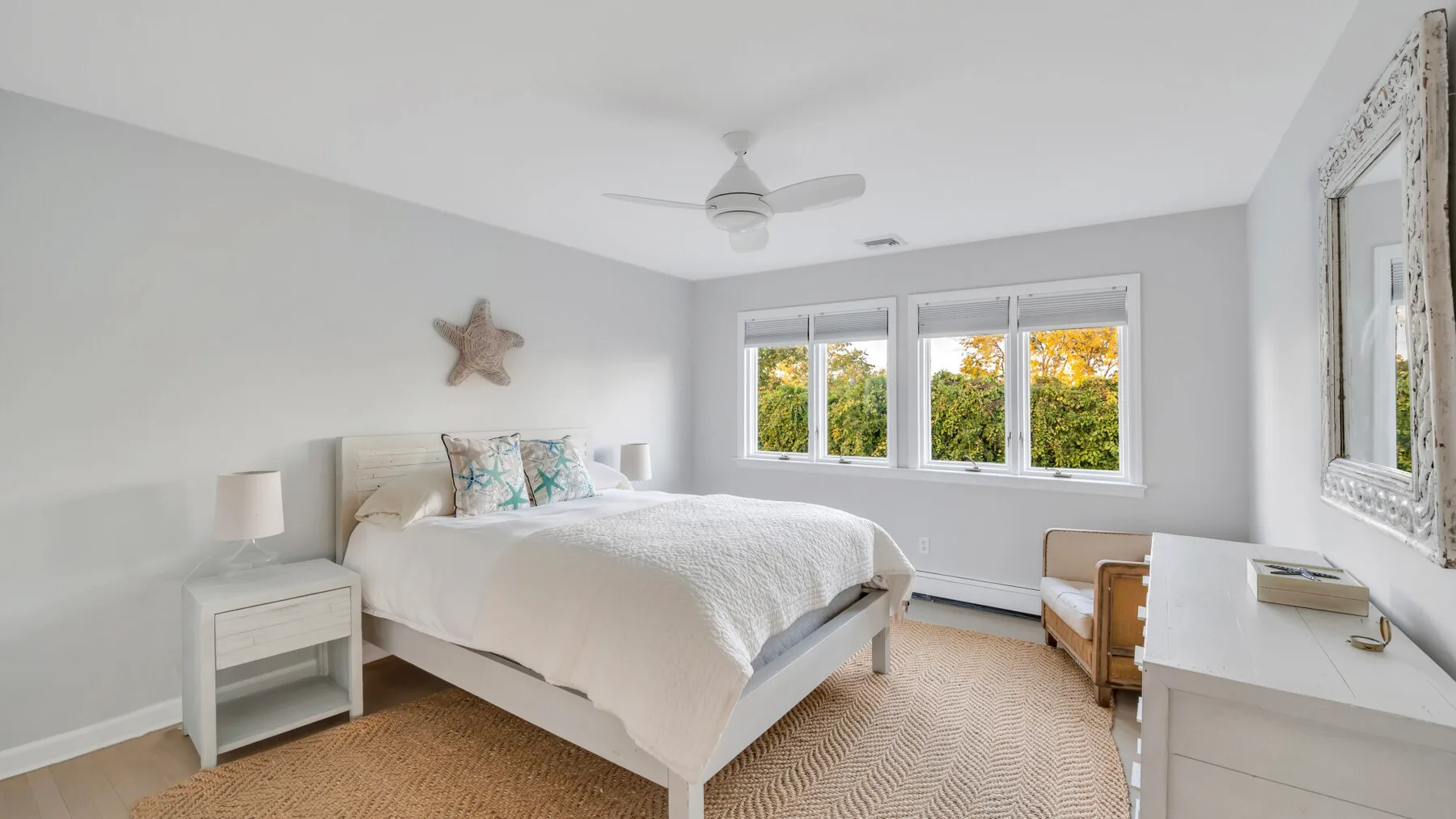 Un dormitorio luminoso con una cama bien tendida y ventanas amplias.