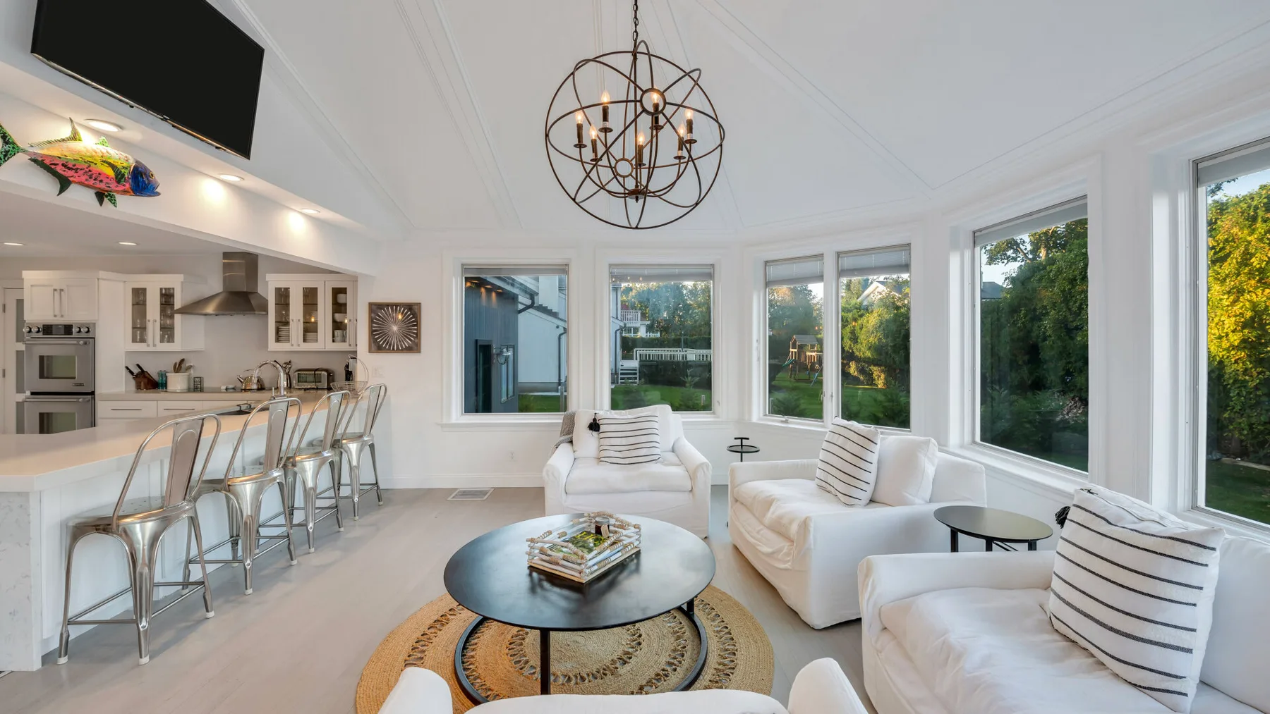 Una sala luminosa con asientos blancos y grandes ventanas que dan a árboles verdes.