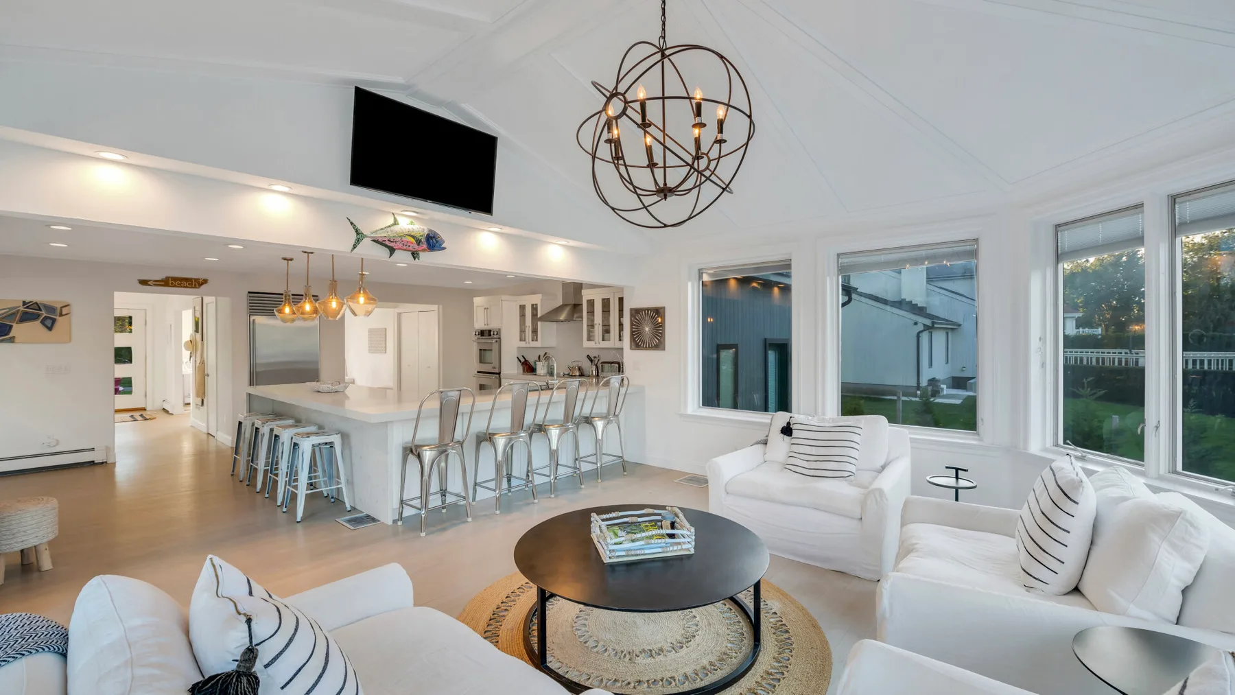 Una sala de estar y cocina de planta abierta con una isla y asientos.
