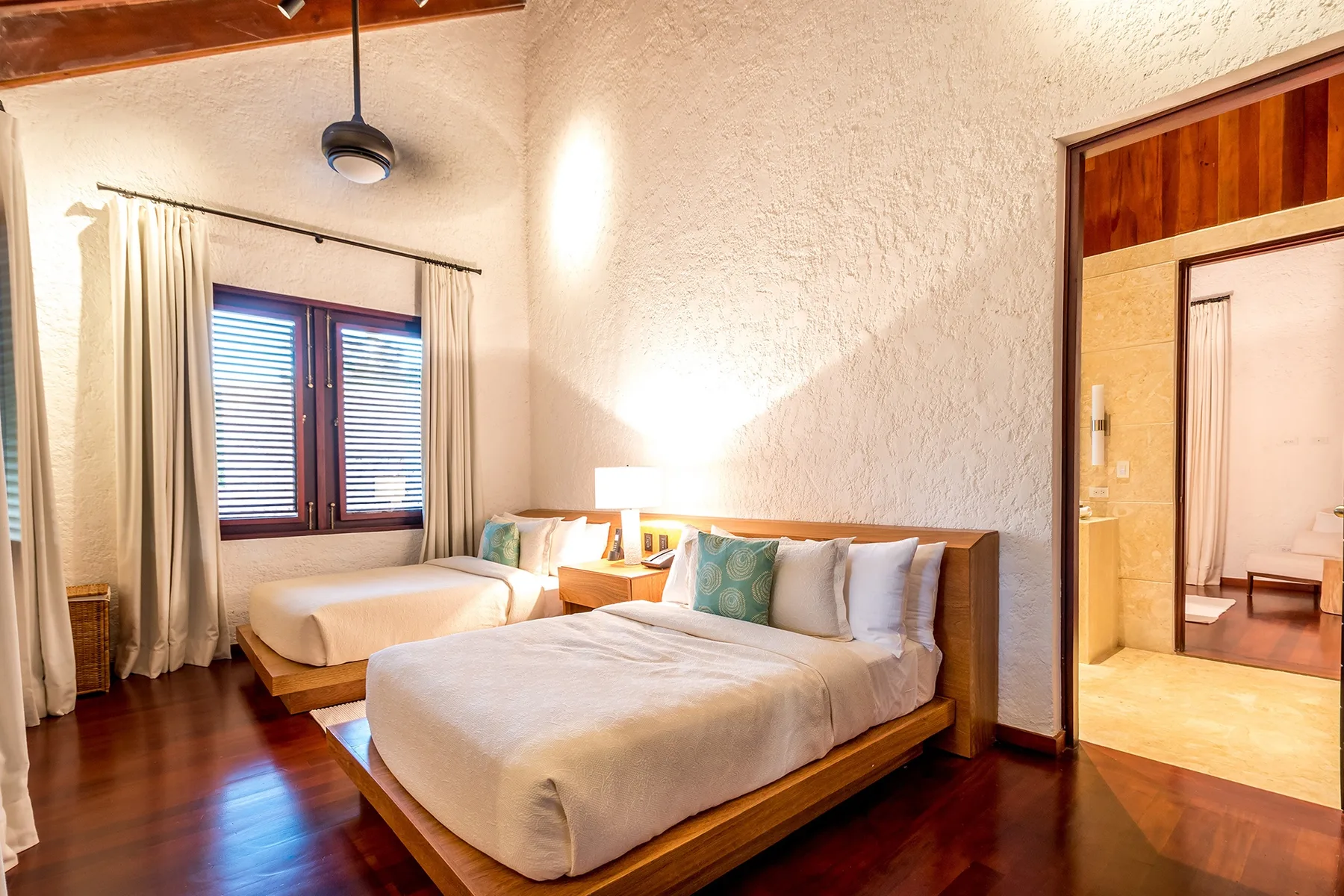 A bedroom with two beds, bedside tables, and a window with curtains.