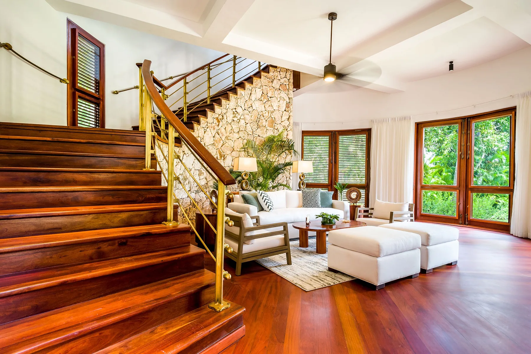 A bright living room with a wooden staircase and seating area.
