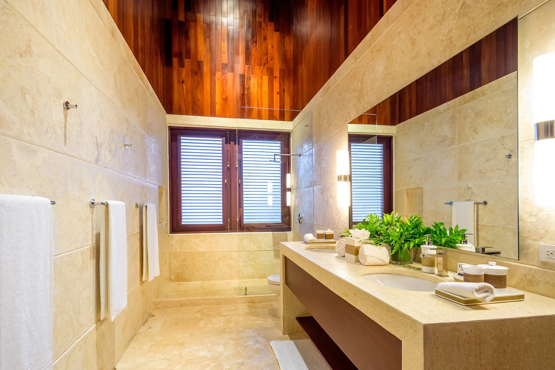 A spacious bathroom has a long vanity, a large mirror, and a window.