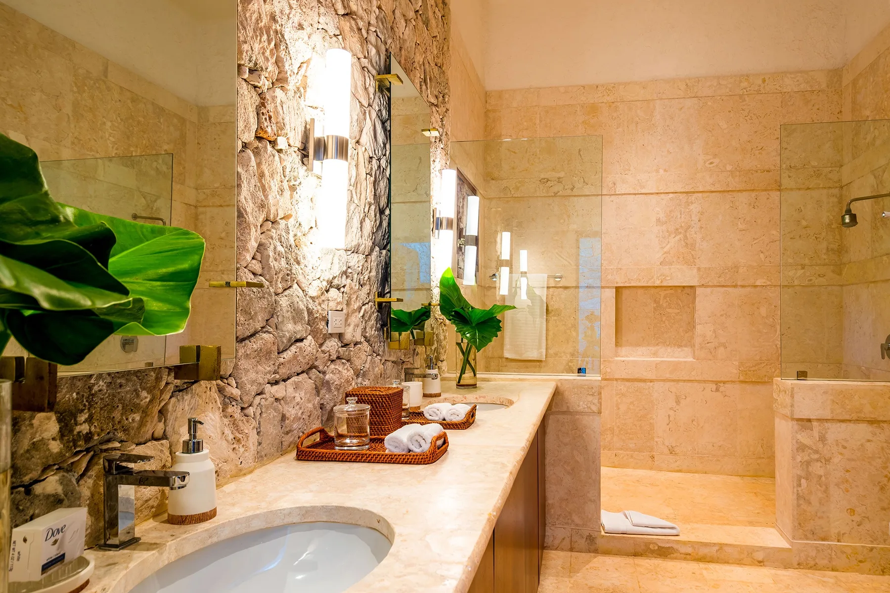 A stone-accented bathroom with a sink, large mirror, and walk-in shower.
