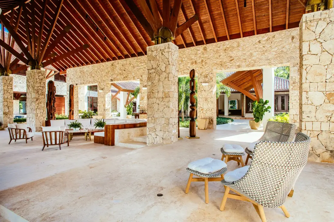 An open-air lobby with stone walls, wooden beams, and seating.