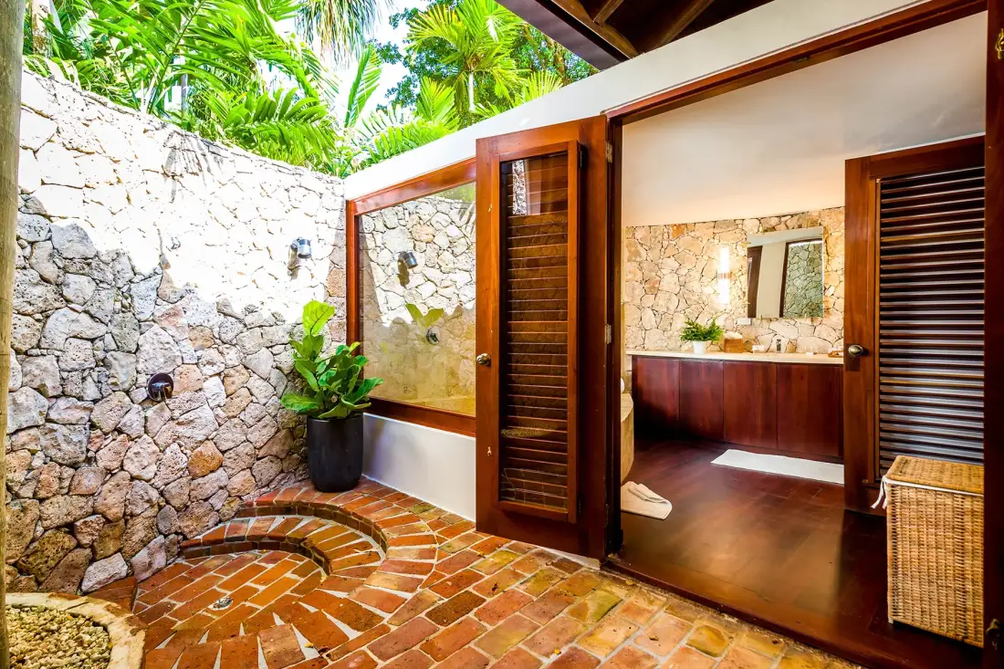 An open-air bathroom with a stone wall and a sink vanity.