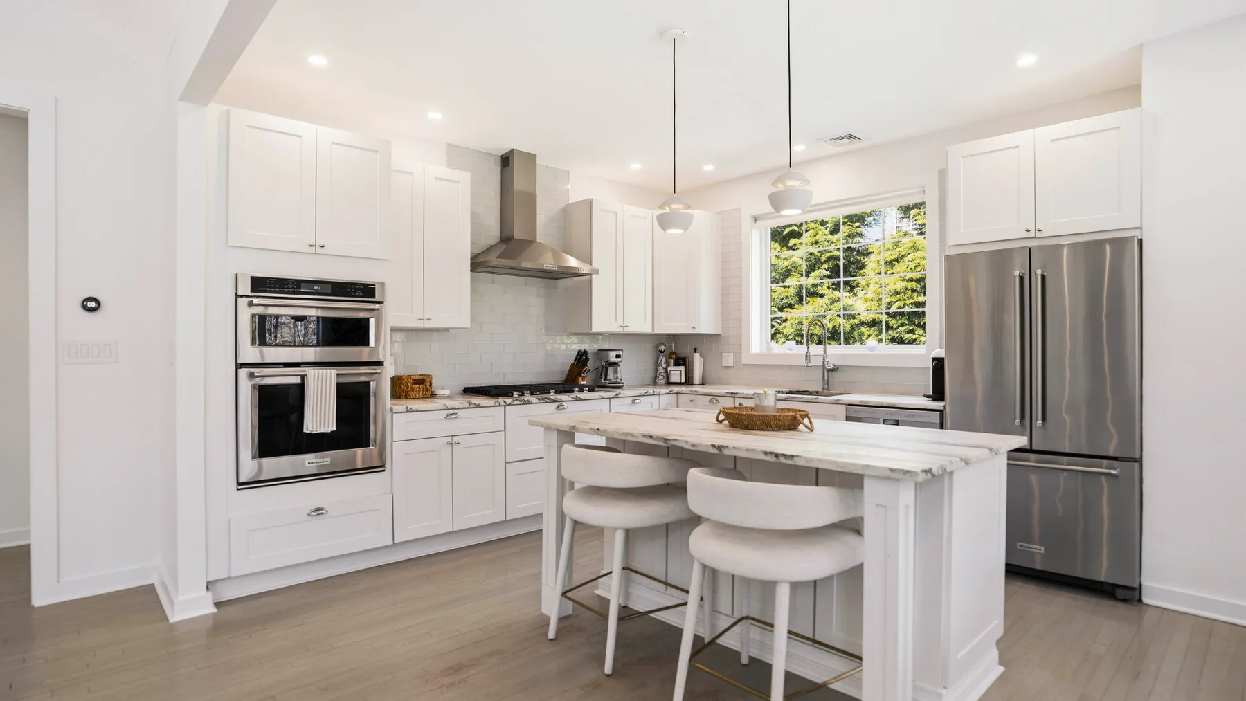 Una cocina luminosa con gabinetes blancos, una isla central y electrodomésticos de acero inoxidable.