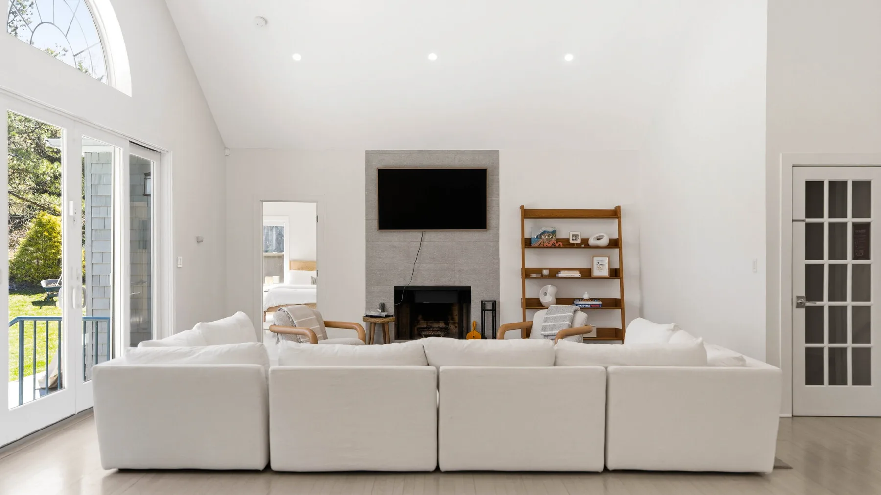 Una sala luminosa con una amplia zona de asientos frente a una chimenea y un televisor.
