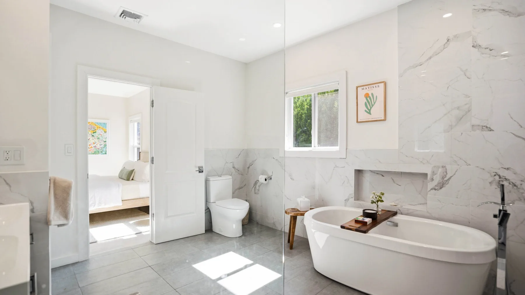 Un baño luminoso con una bañera exenta y paredes con acabado tipo mármol.