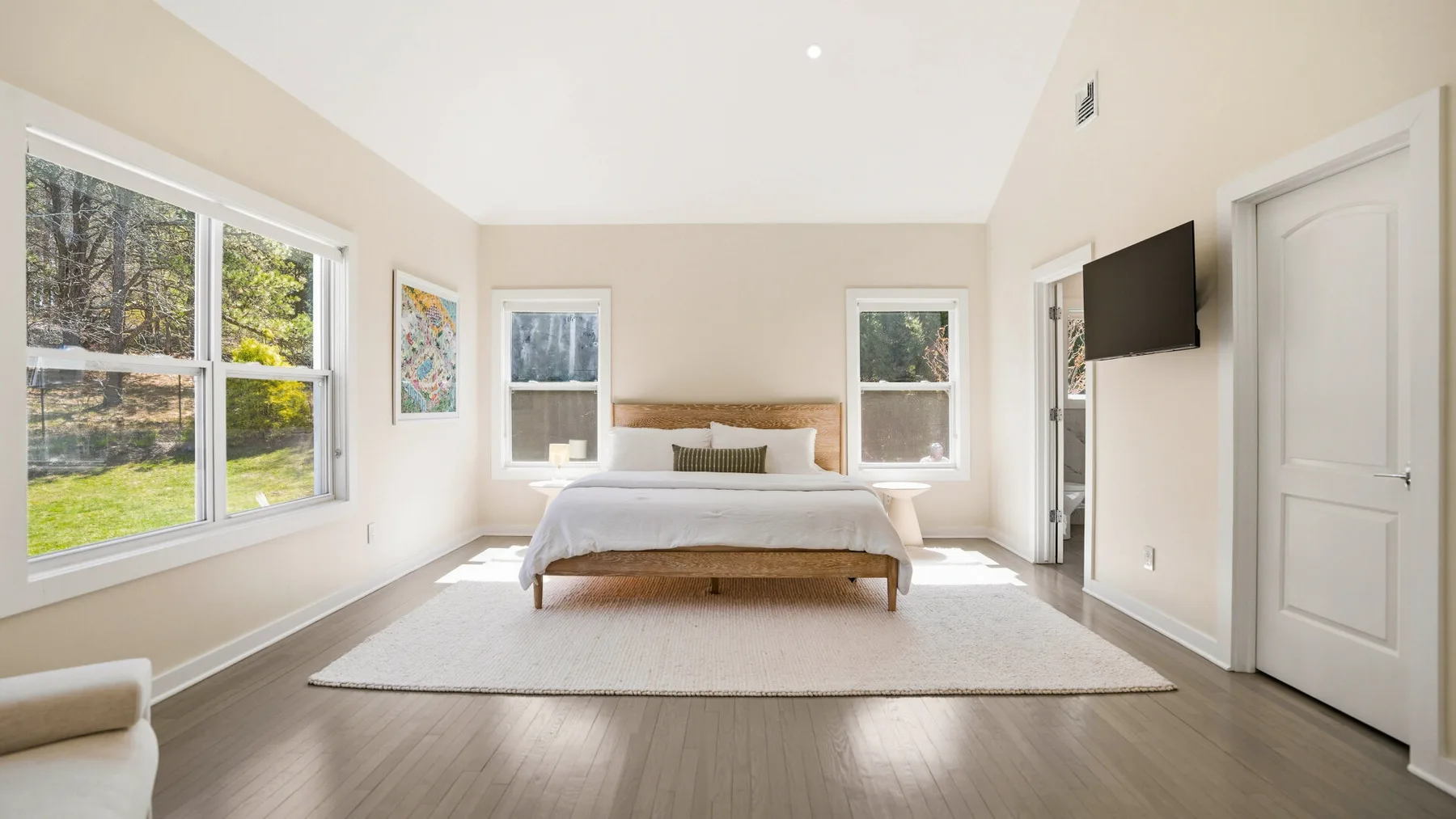 Un dormitorio luminoso con una cama centrada sobre una alfombra grande.