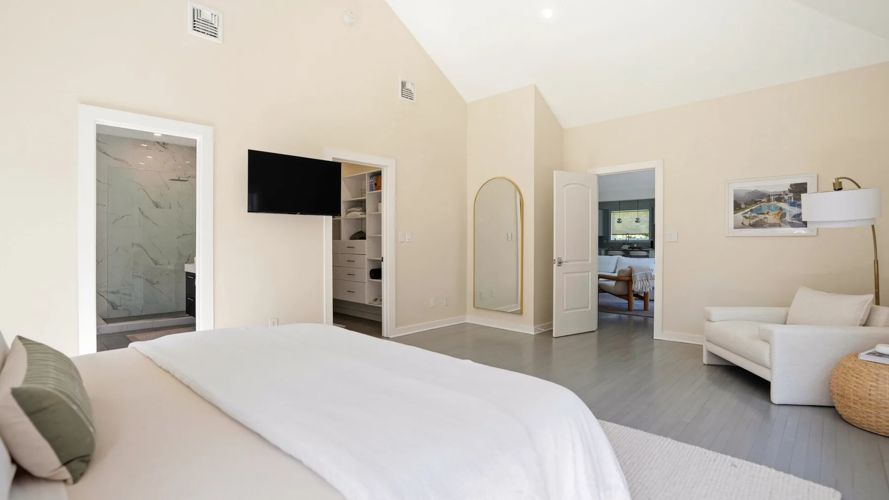Un dormitorio luminoso con una cama grande y una zona de estar junto a la puerta.