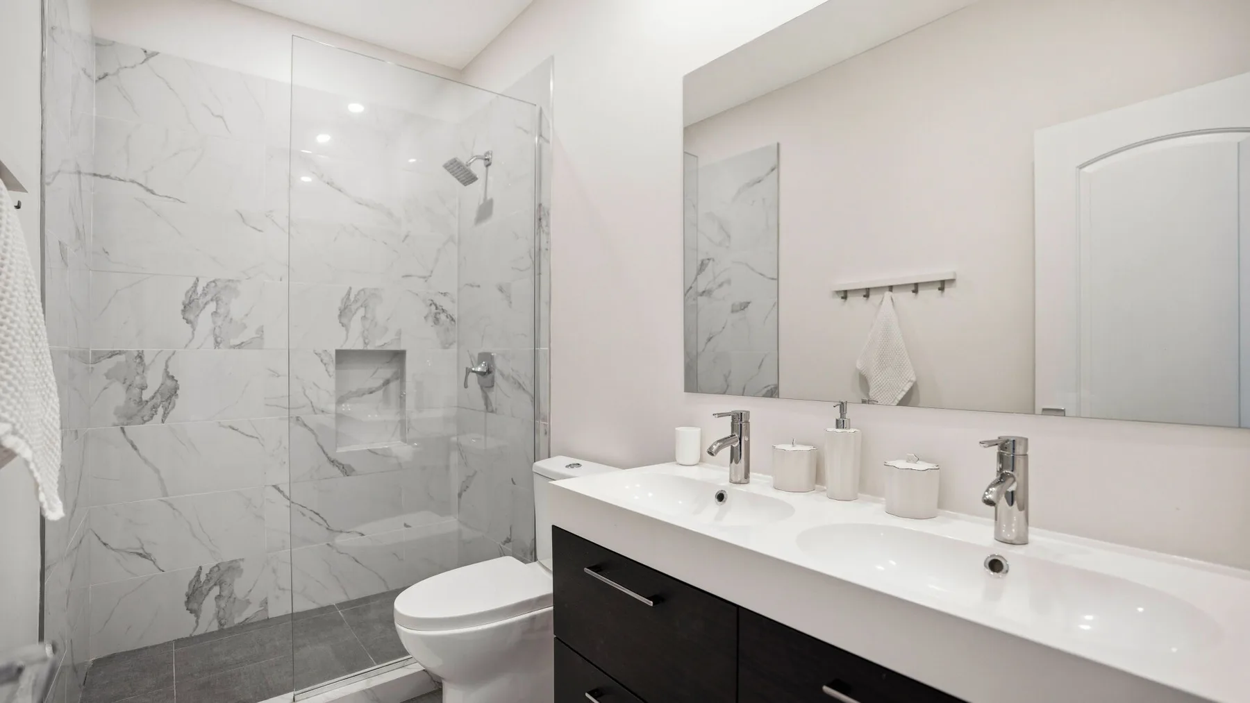 Un baño moderno con ducha de vidrio y un tocador alargado.