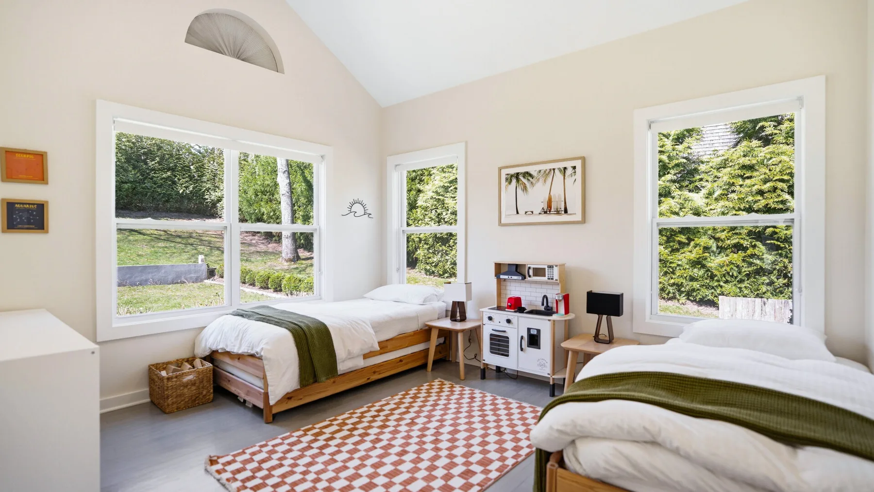 Un dormitorio luminoso con dos camas y grandes ventanas con vistas a la vegetación.