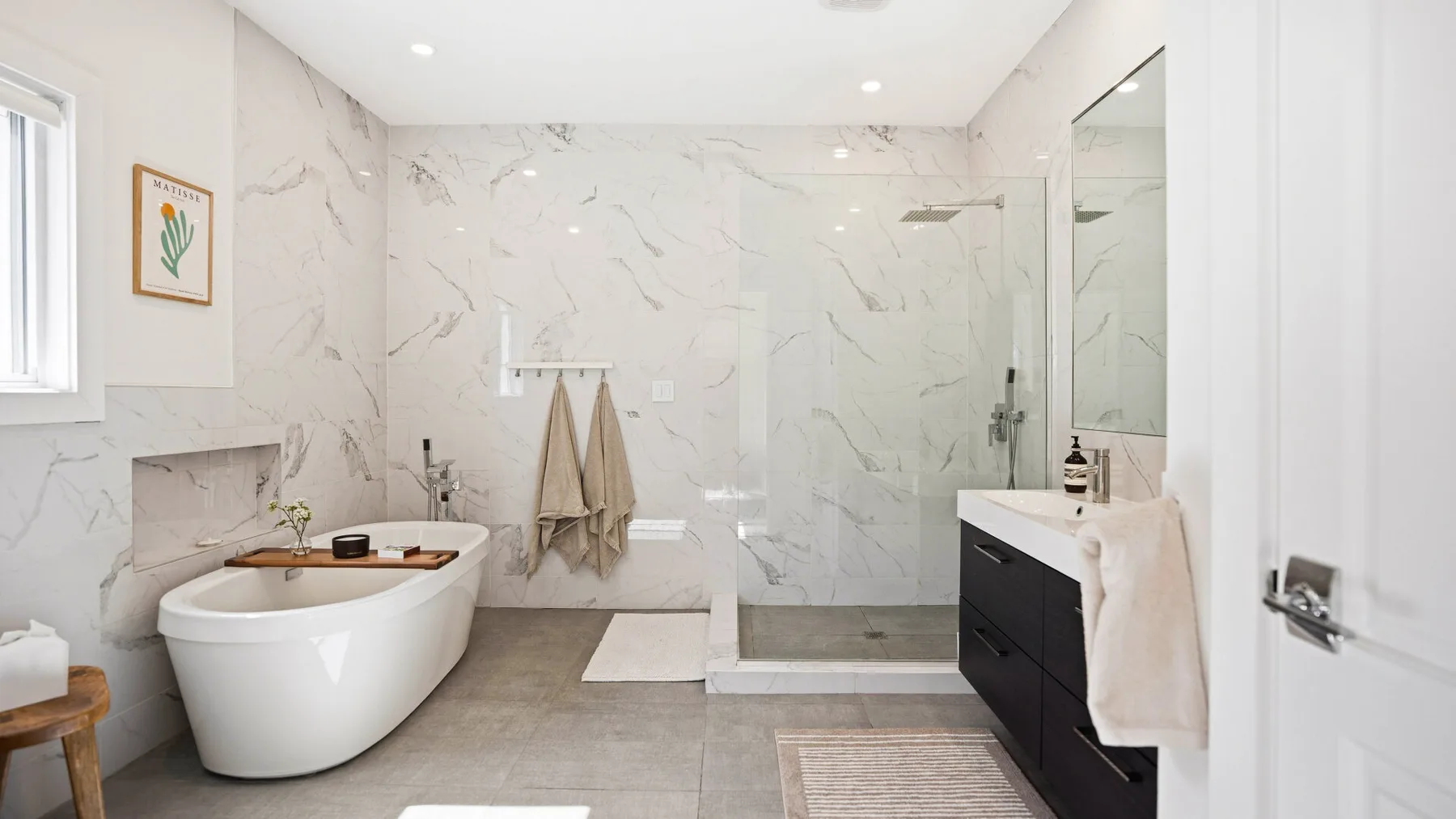 Un baño luminoso con bañera, ducha de vidrio y tocador.