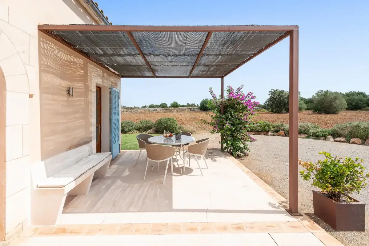 A shaded patio with outdoor seating overlooks a dry, open landscape.
