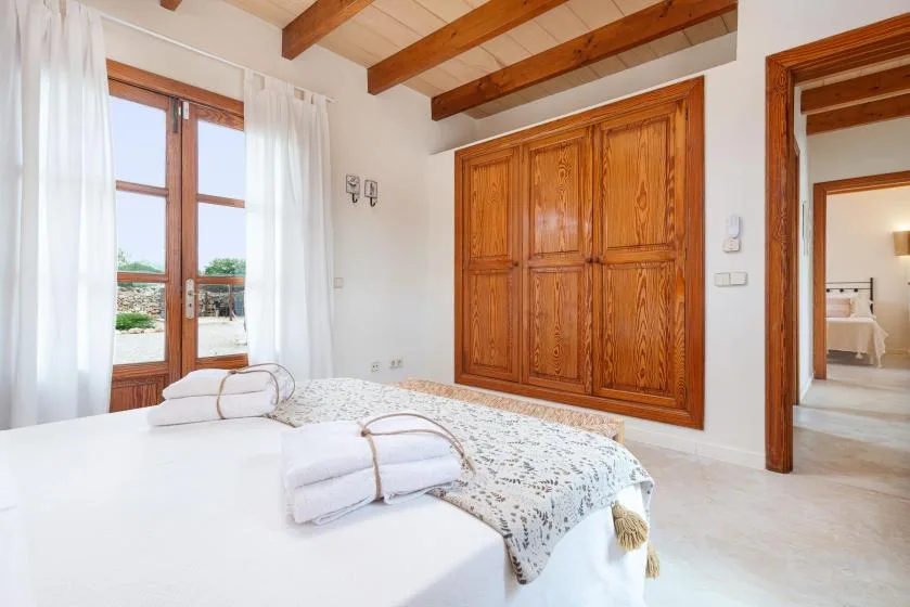 A bedroom with a bed, folded towels, and a large wooden wardrobe.