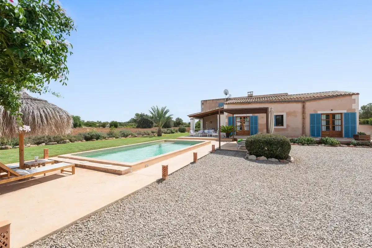 A house and swimming pool sit beside a wide gravel courtyard.