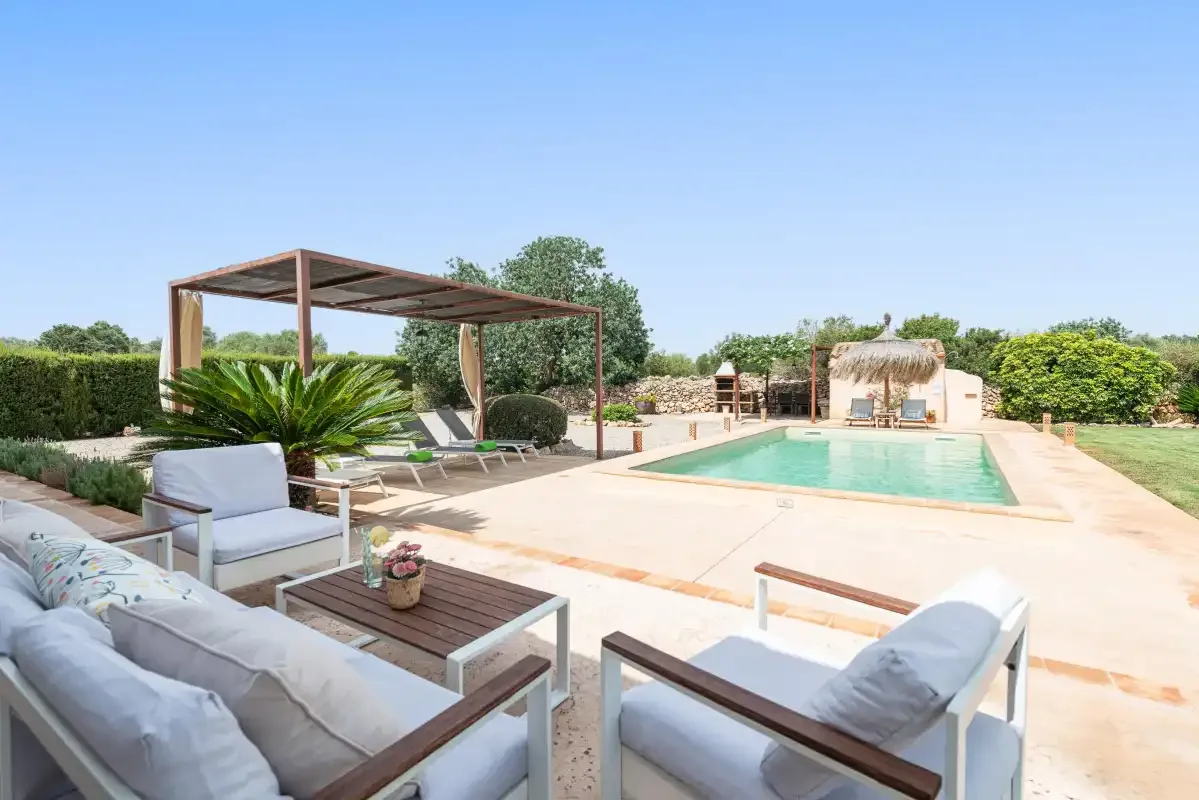 An outdoor pool sits beside a shaded seating area and landscaped garden.