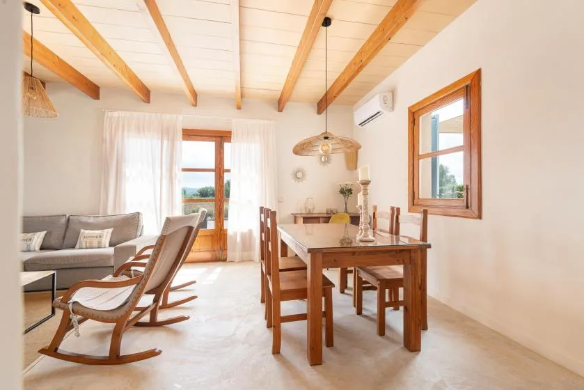 A bright living and dining room with wooden seating and a table.