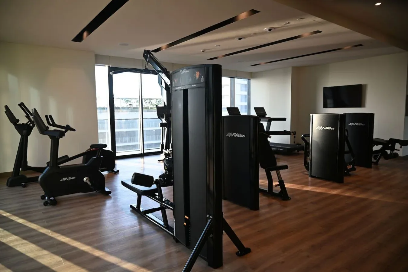 Una sala de ejercicio con máquinas y grandes ventanas.