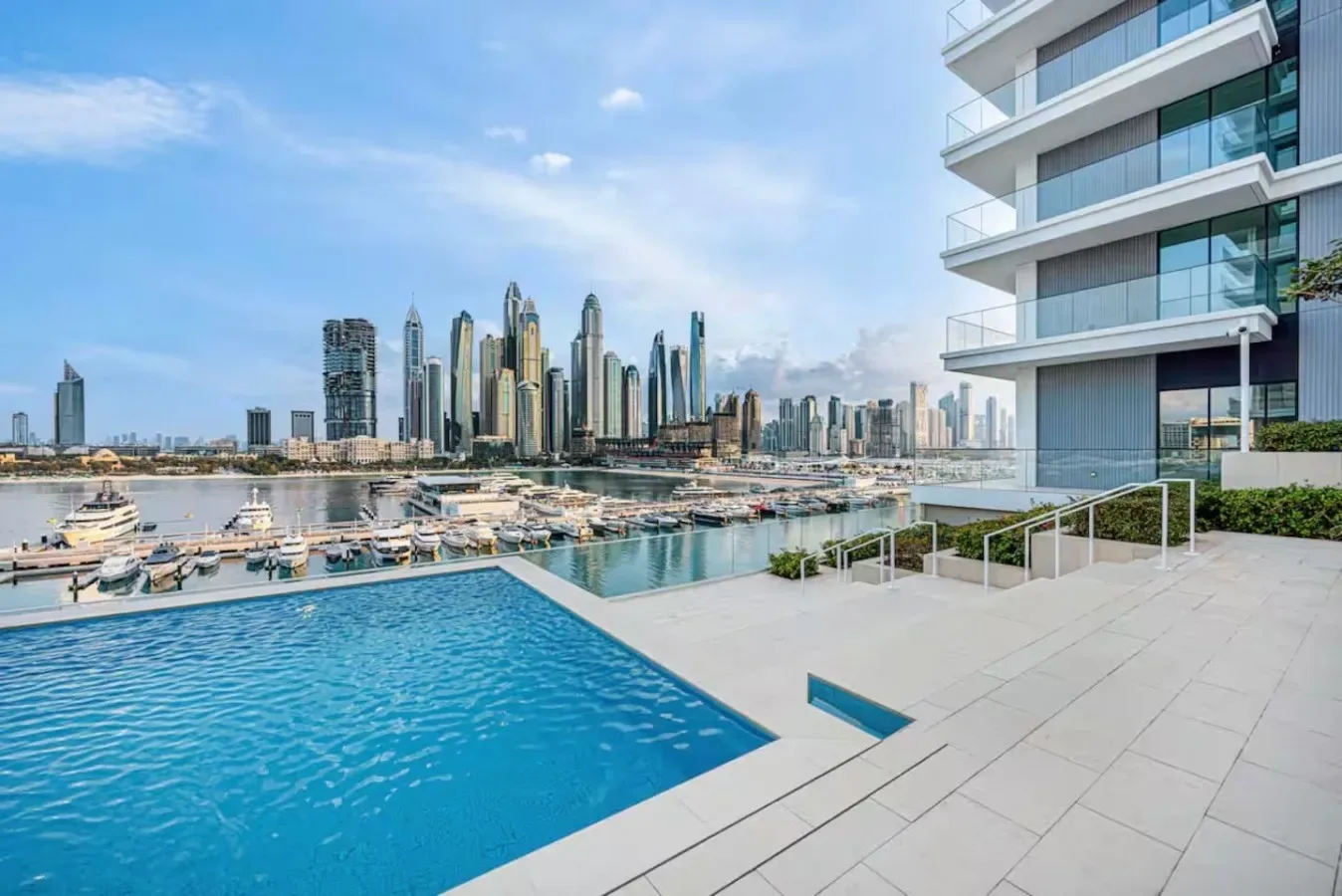 Una piscina al aire libre da a una marina y al perfil urbano.