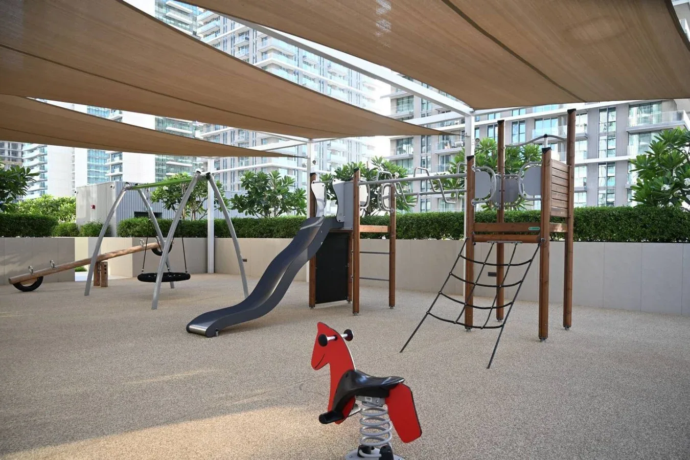 Un parque infantil al aire libre con toboganes y equipo para trepar bajo toldos.