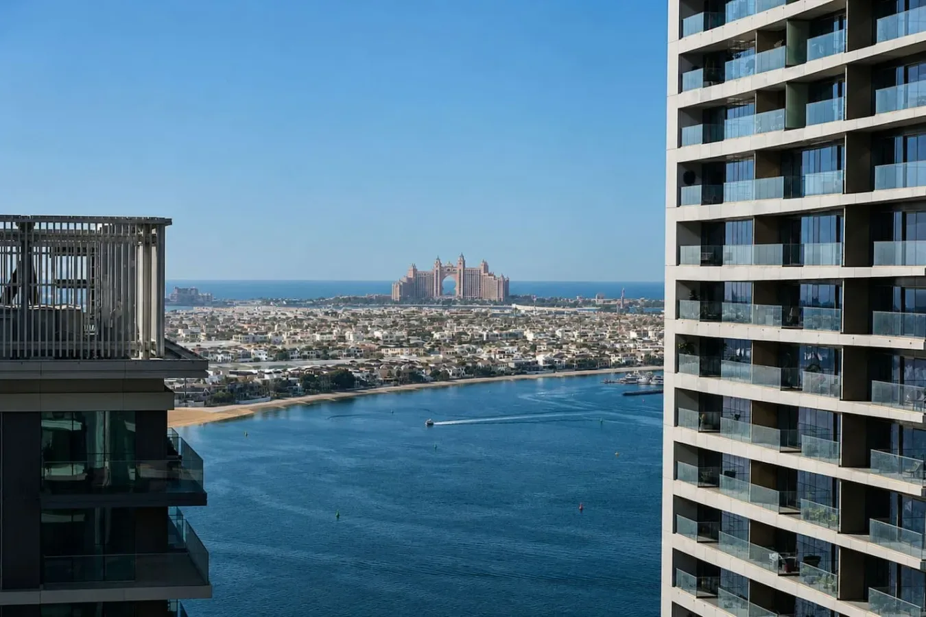 Vista de una ciudad junto al agua entre edificios altos, con agua azul y un horizonte distante.