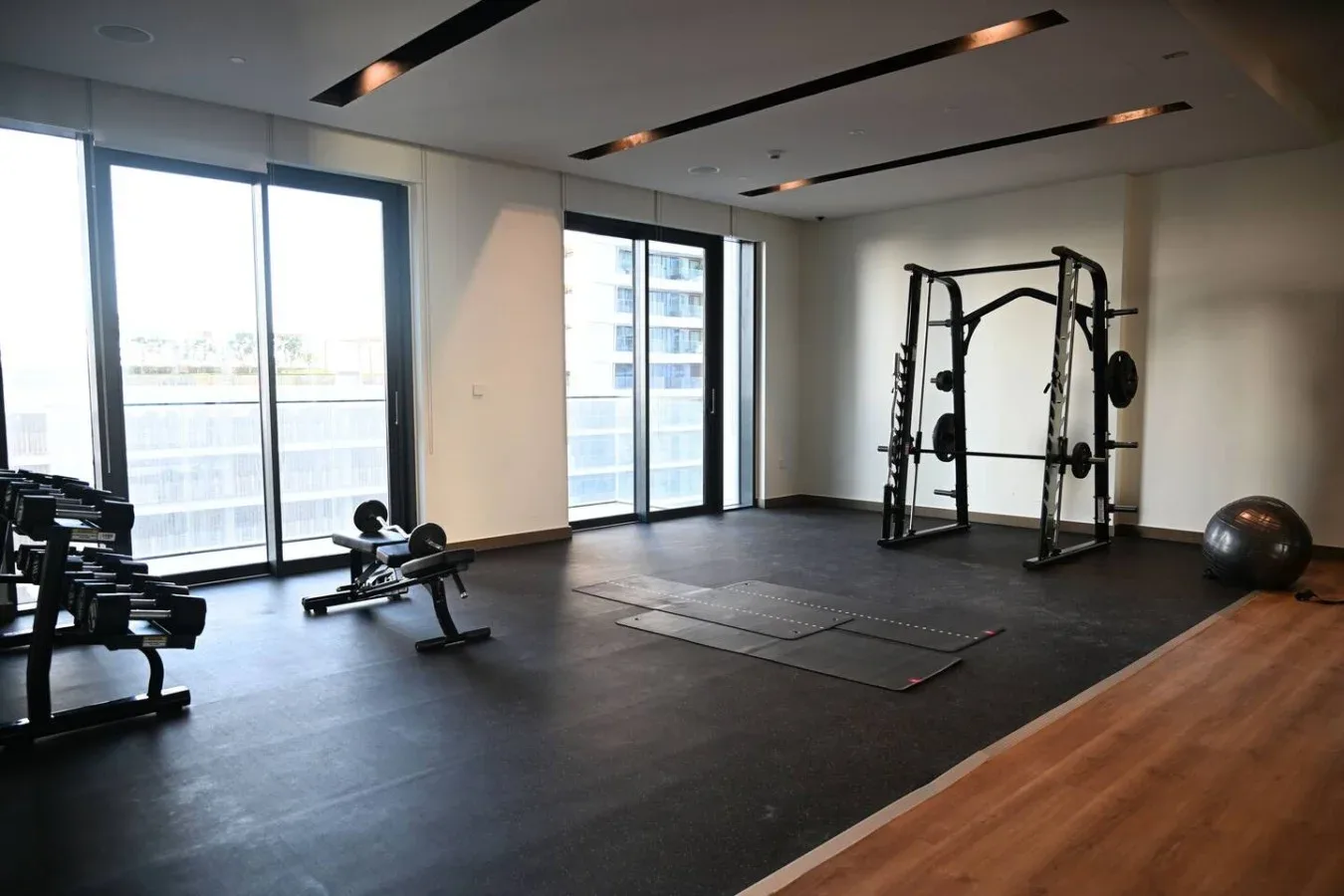Una sala de ejercicios luminosa con equipo de entrenamiento y una ventana grande.
