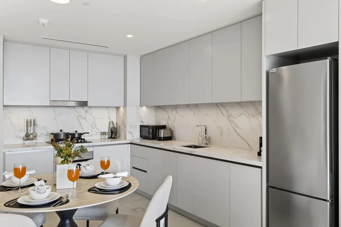 Una cocina moderna con gabinetes grises y una mesa puesta para comer.