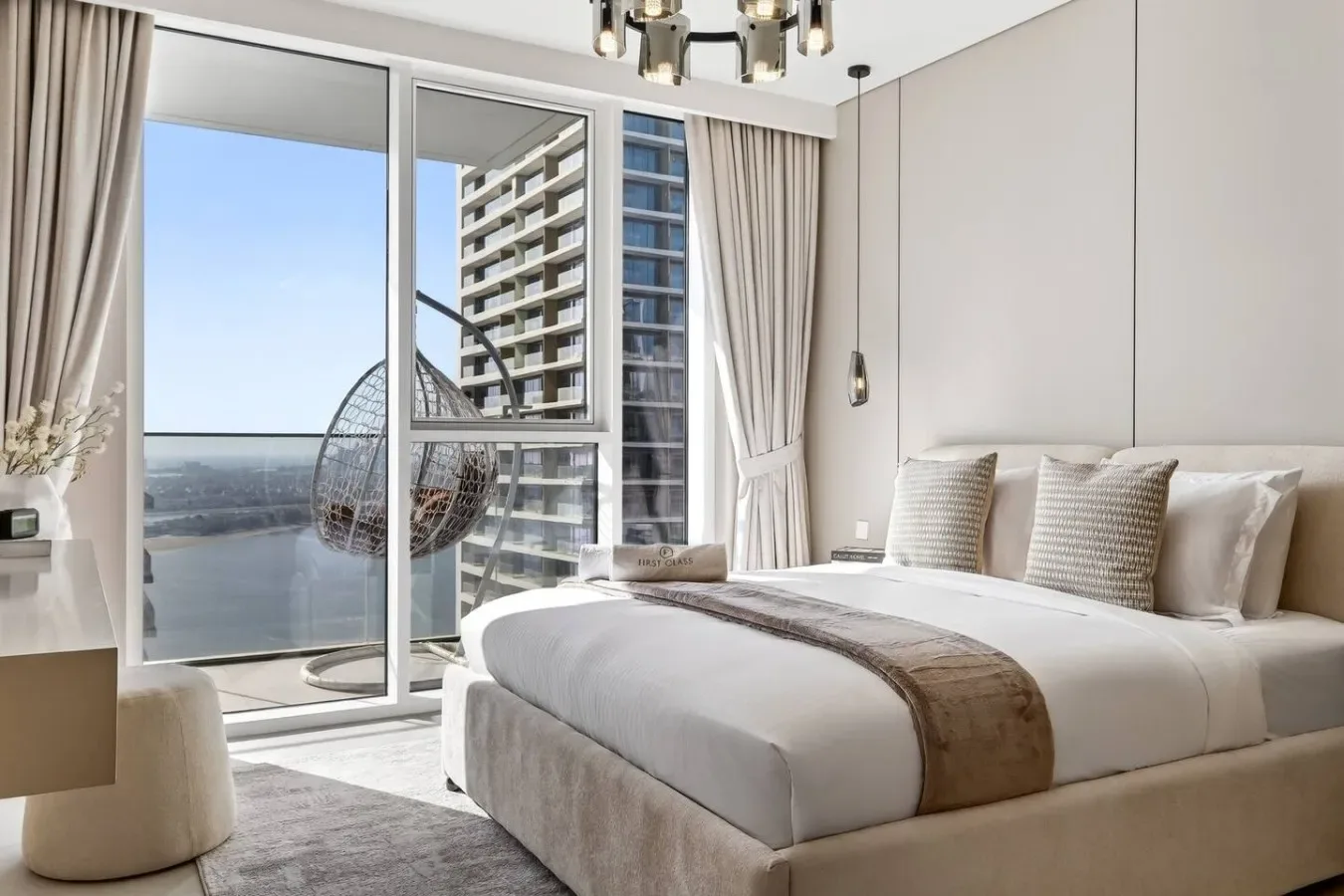 Un dormitorio luminoso con una cama grande junto a ventanales con vistas al agua.